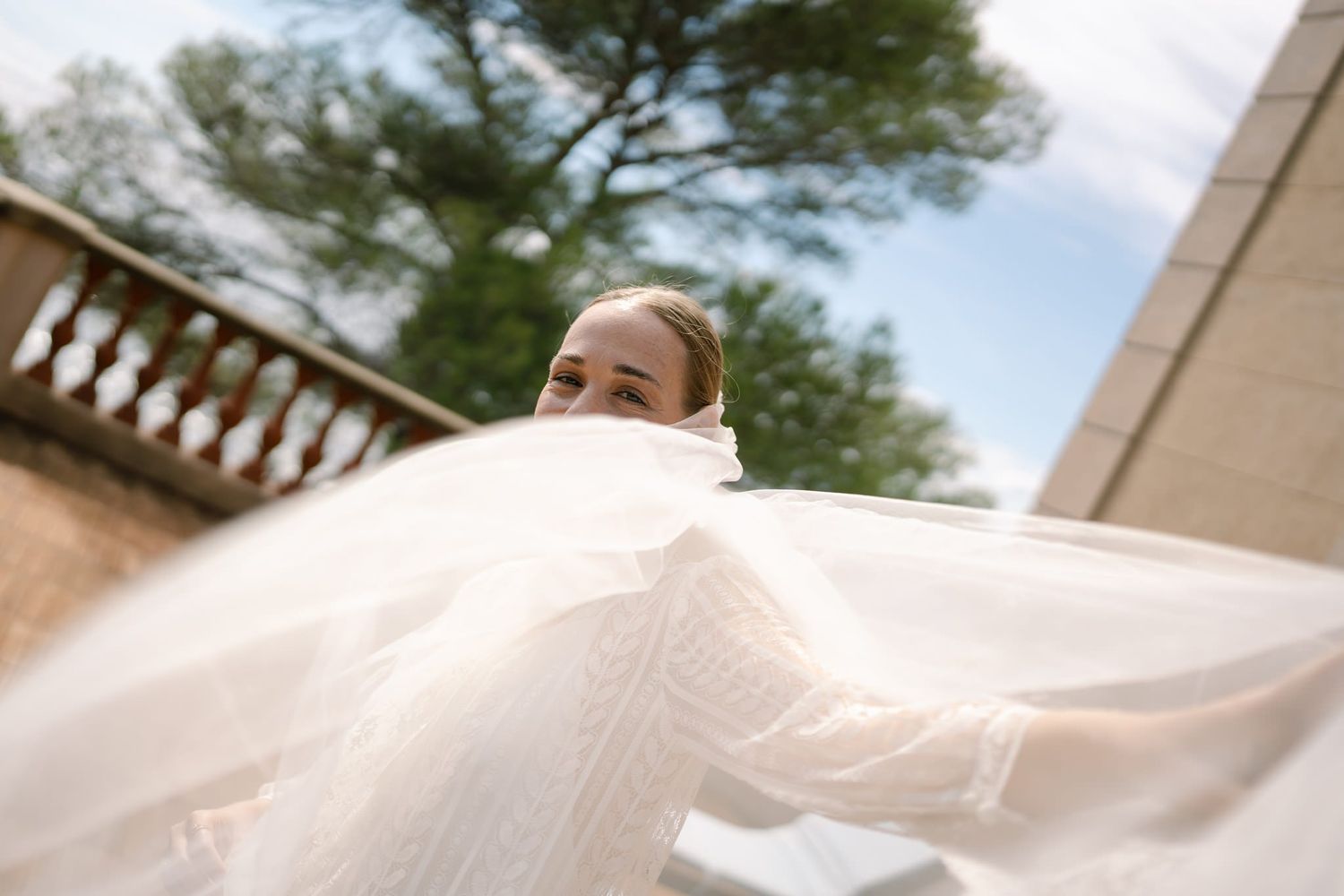 Flowing white fabric of a wedding dress captured in motion against a bright background.