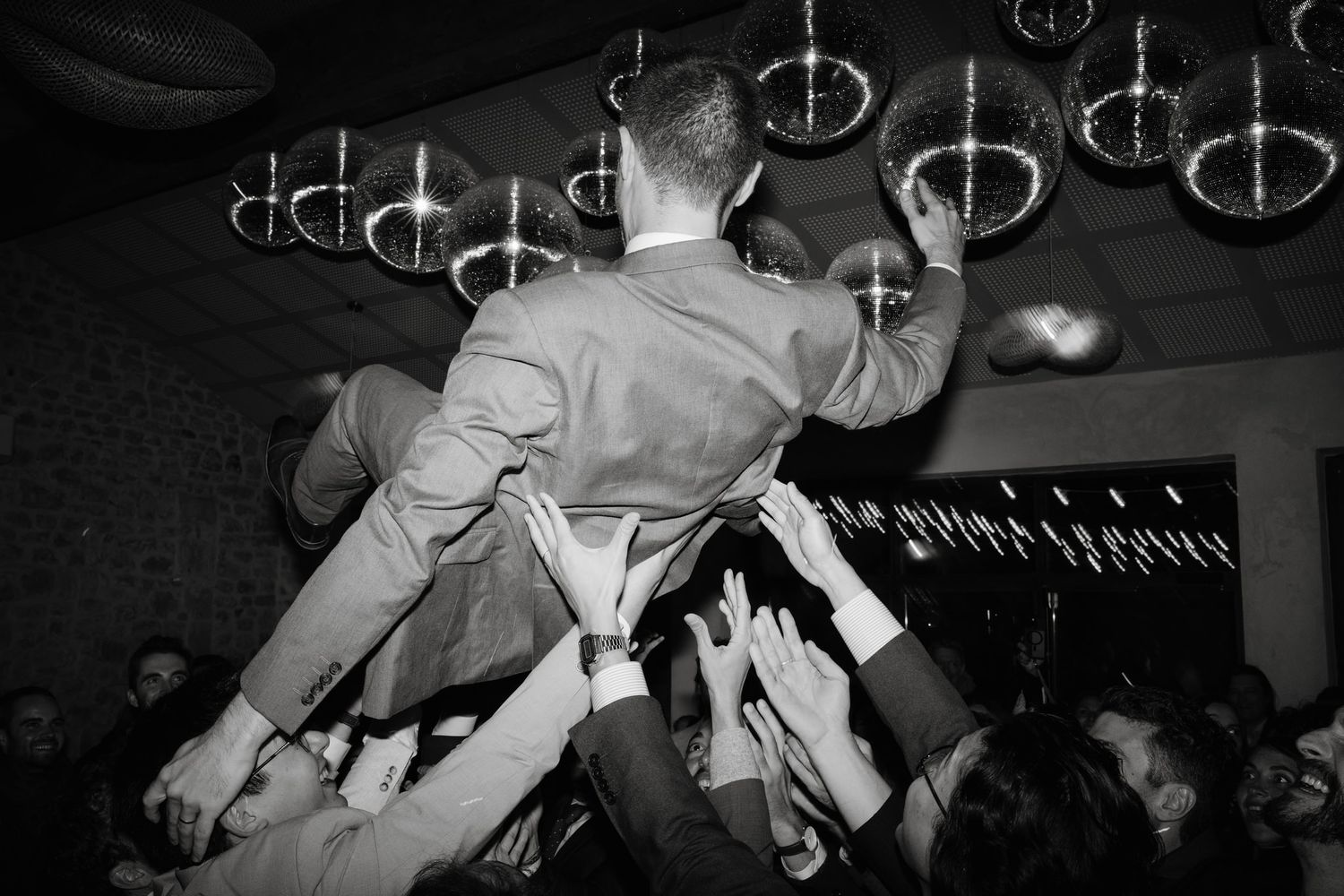 Black and white photo of people dancing energetically at a wedding reception.