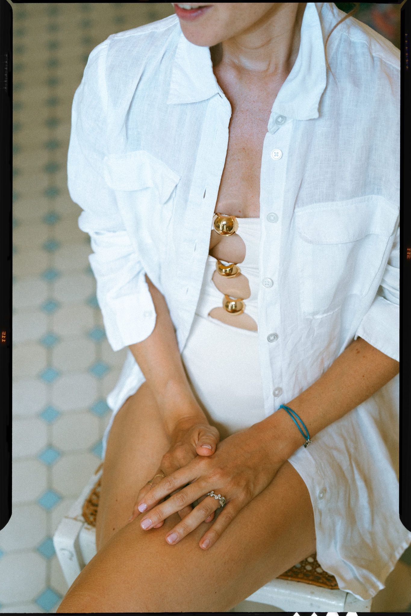 Person wearing a crisp white button-down shirt and jewelry in a casual pose.