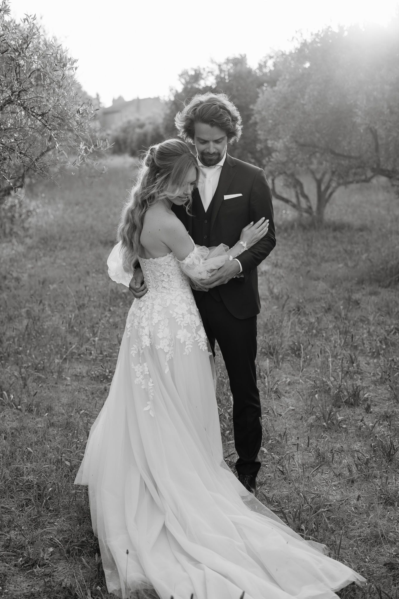 Black and white photo of a couple walking together outdoors in wedding attire.