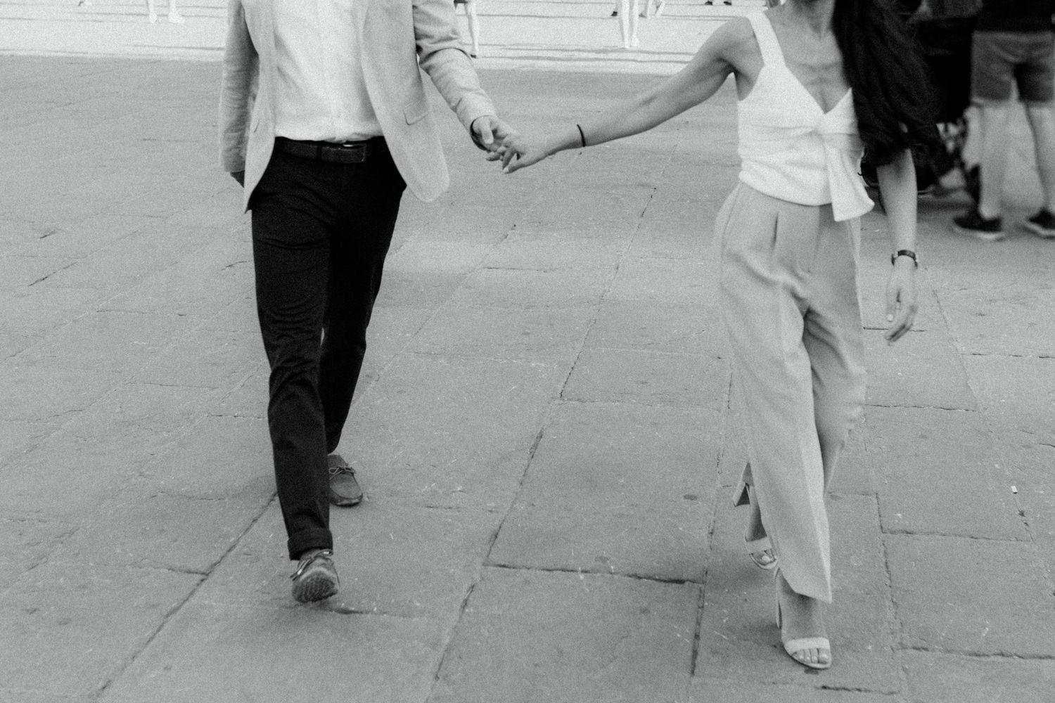 Black and white photo of two people's legs dancing together on a street.