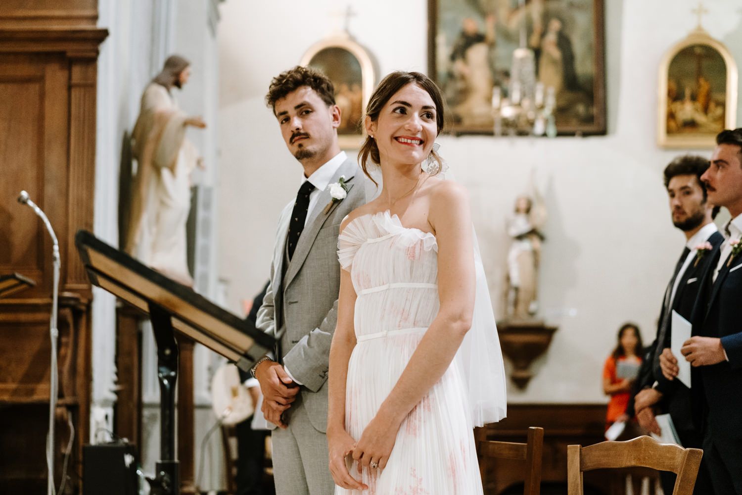 Traditional church wedding ceremony with decorative religious artwork on walls.
