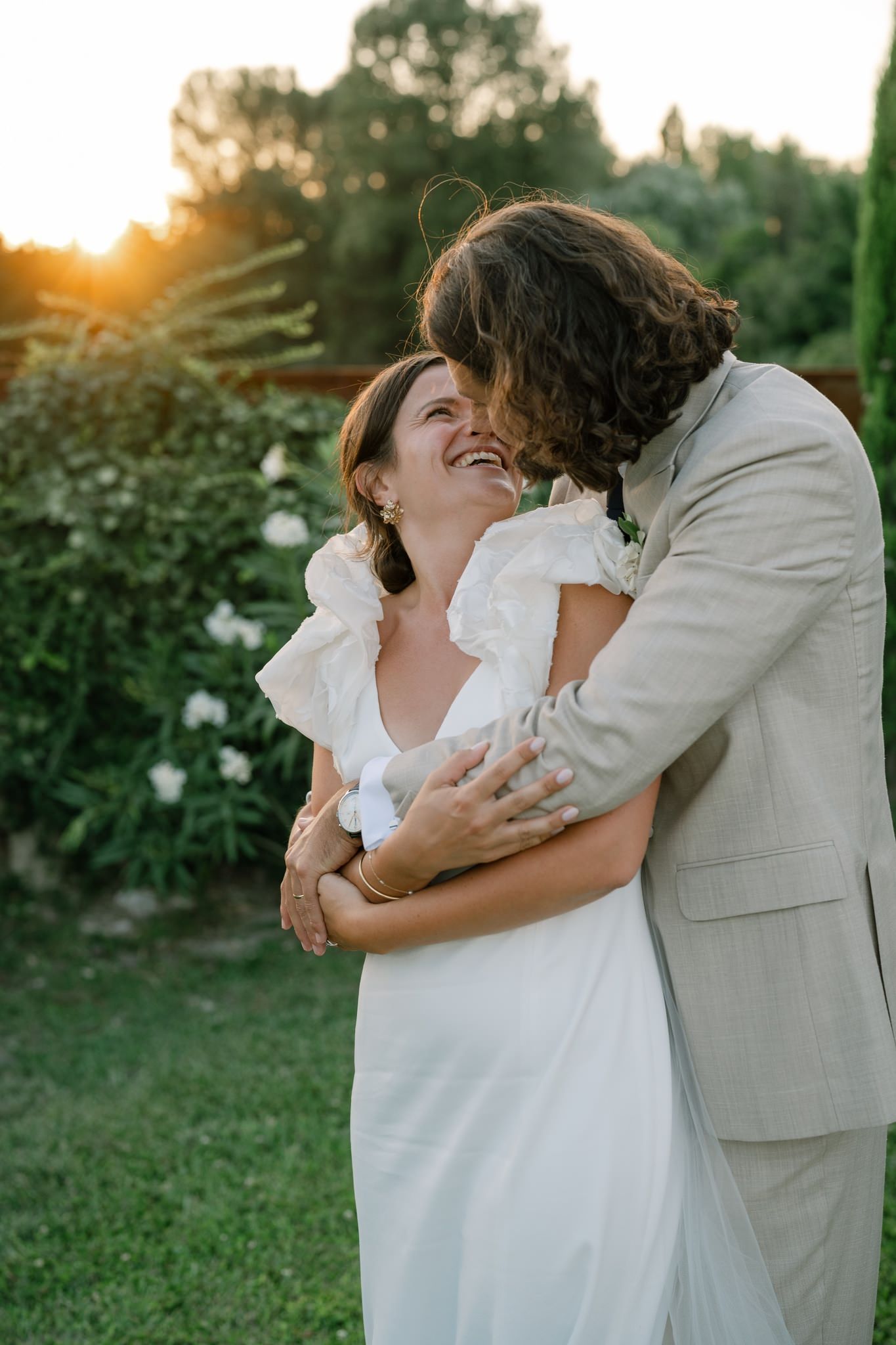 Joyful wedding couple sharing intimate moment during golden hour photoshoot.