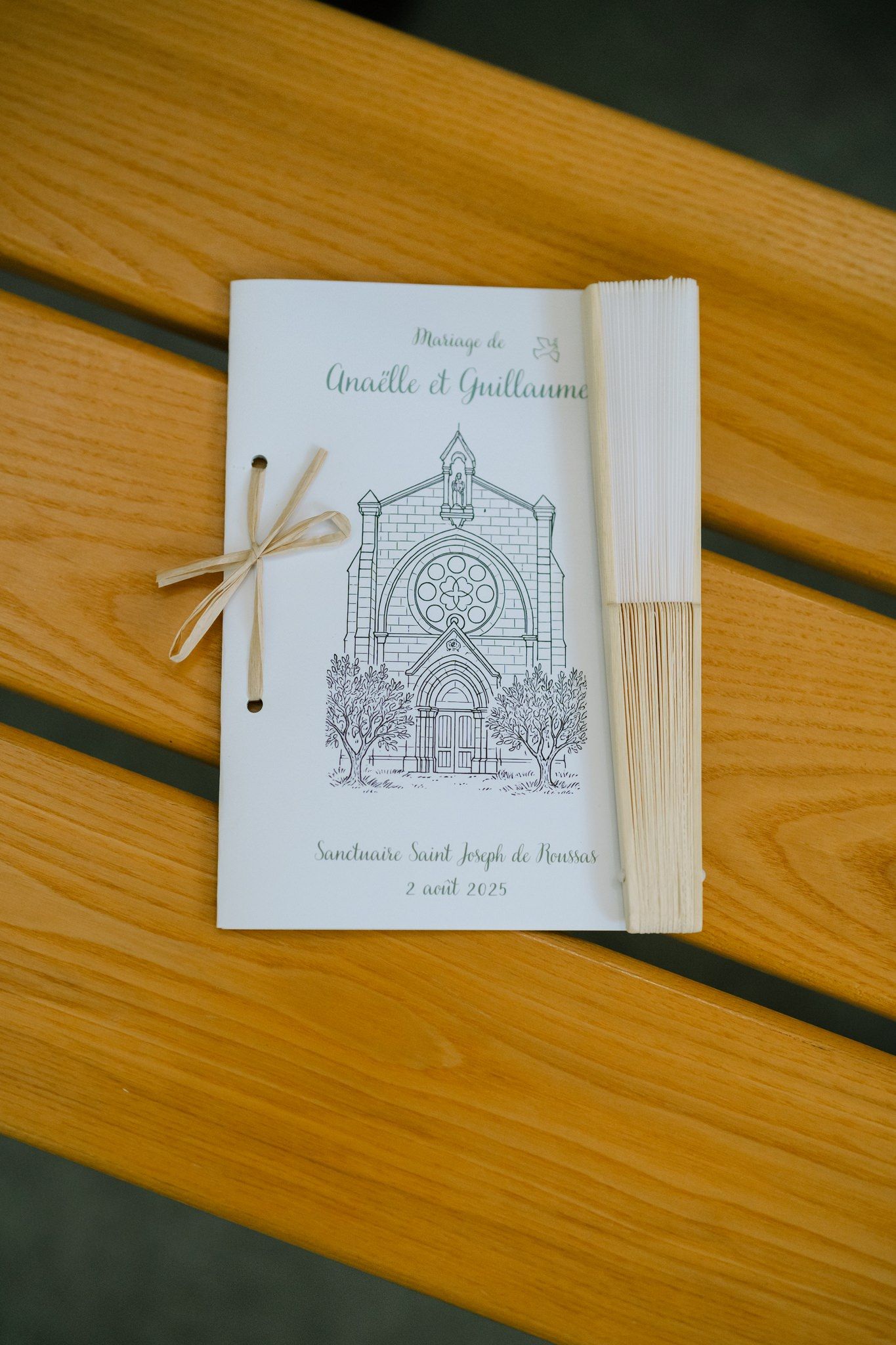 Wedding program featuring delicate church illustration on wooden surface.