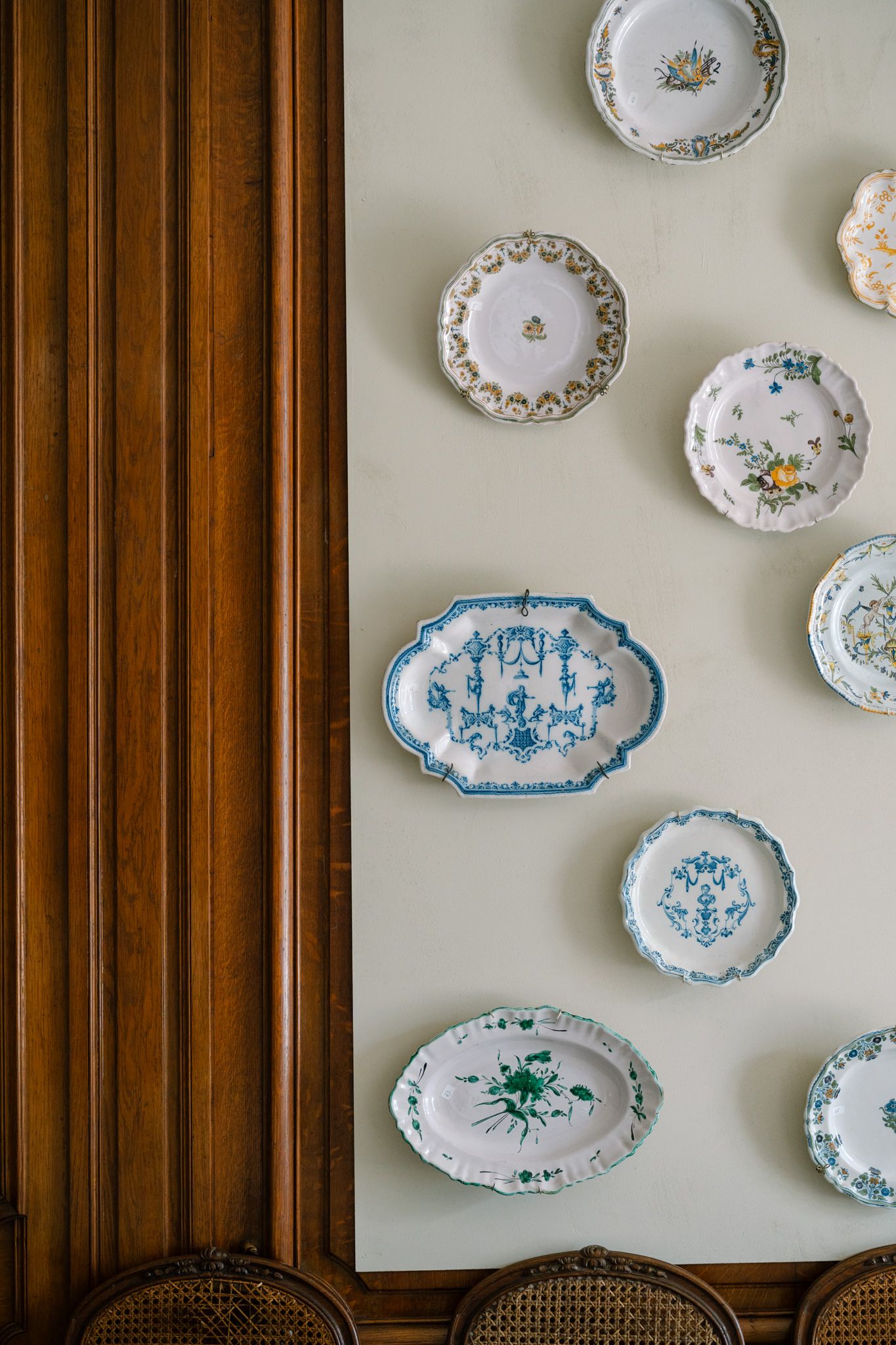 Vintage decorative plates with blue and floral patterns displayed on a wall.