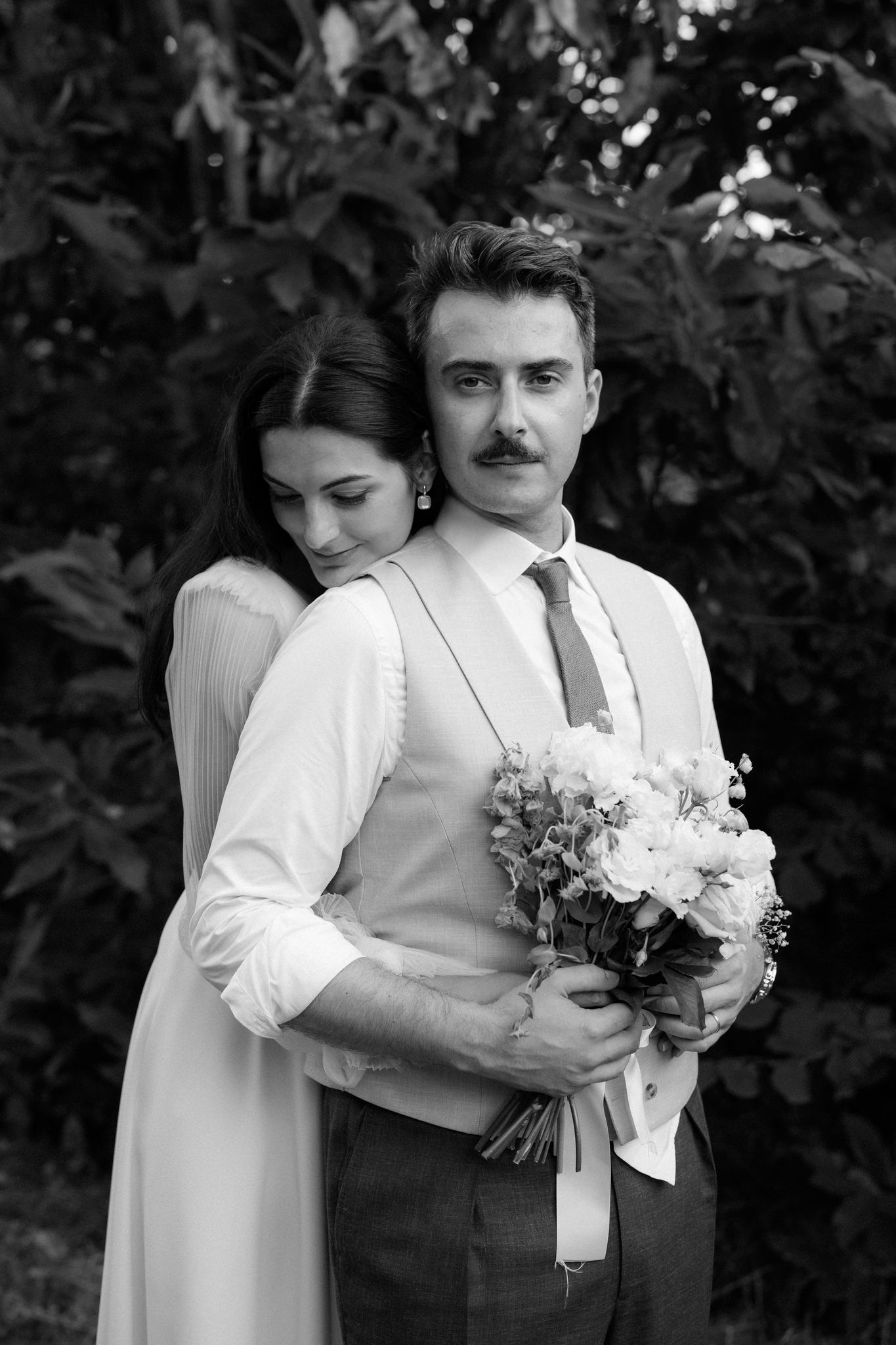 A romantic black and white wedding portrait showing a couple embracing in an intimate moment.
