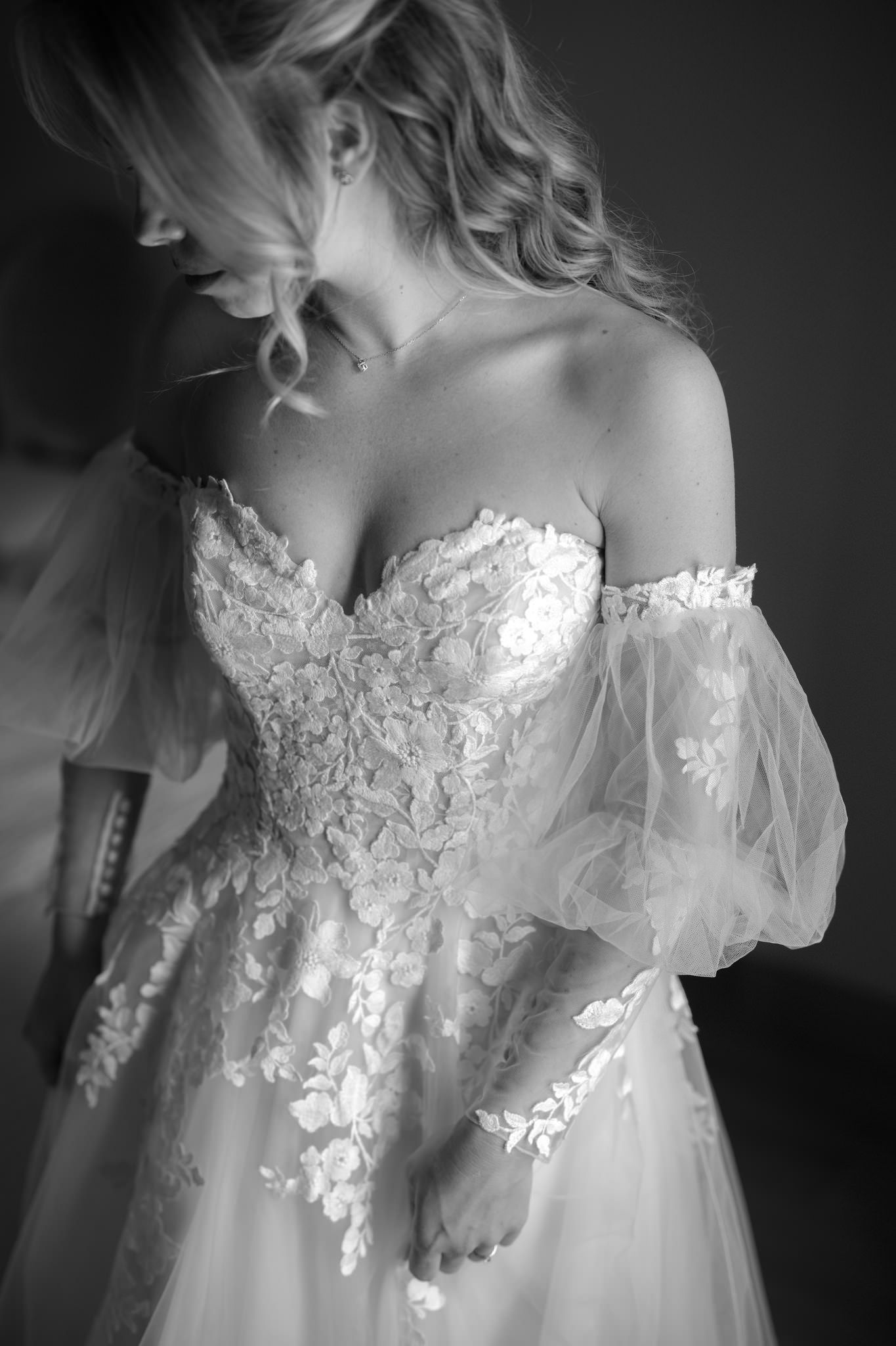 Close-up details of a delicate white lace wedding dress bodice with intricate floral appliques.