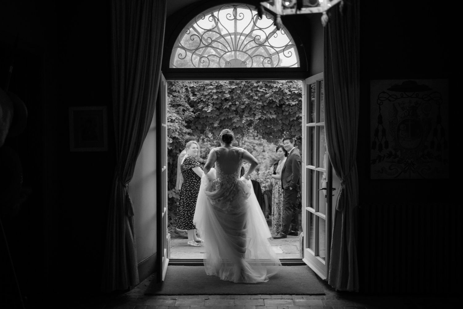 Dramatic black and white silhouette of a bride through an arched doorway.