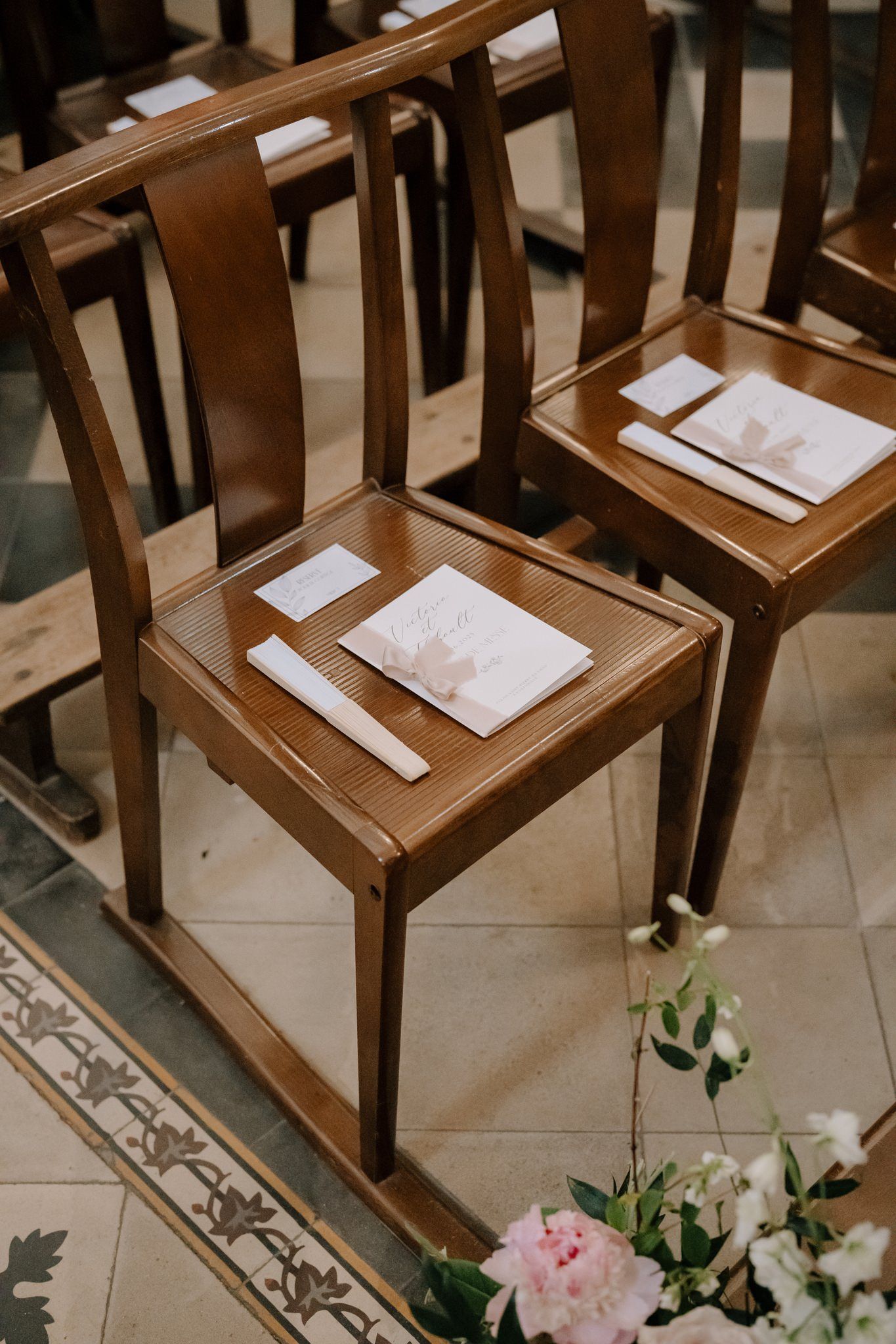 Wooden chairs with ceremony programs set up for a wedding ceremony.