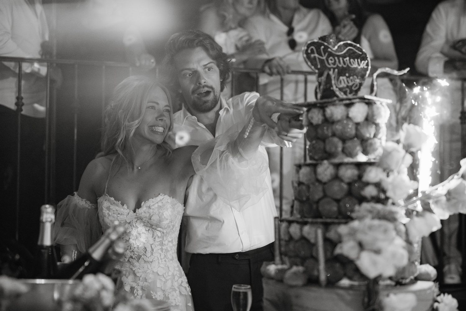 Wedding party dancing and celebrating with sparklers in a dimly lit reception venue.