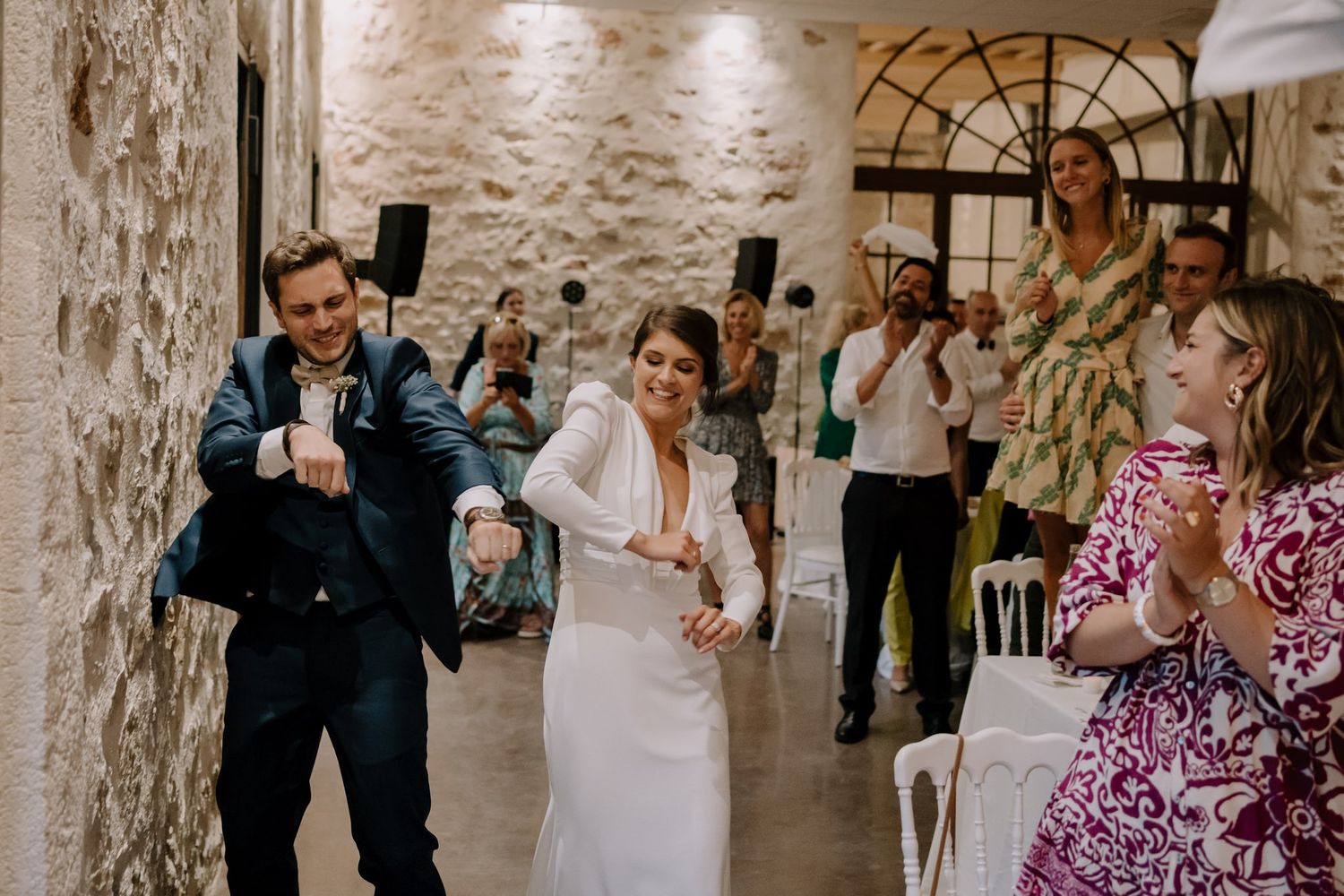Wedding celebration in a rustic stone venue with guests dancing and celebrating.