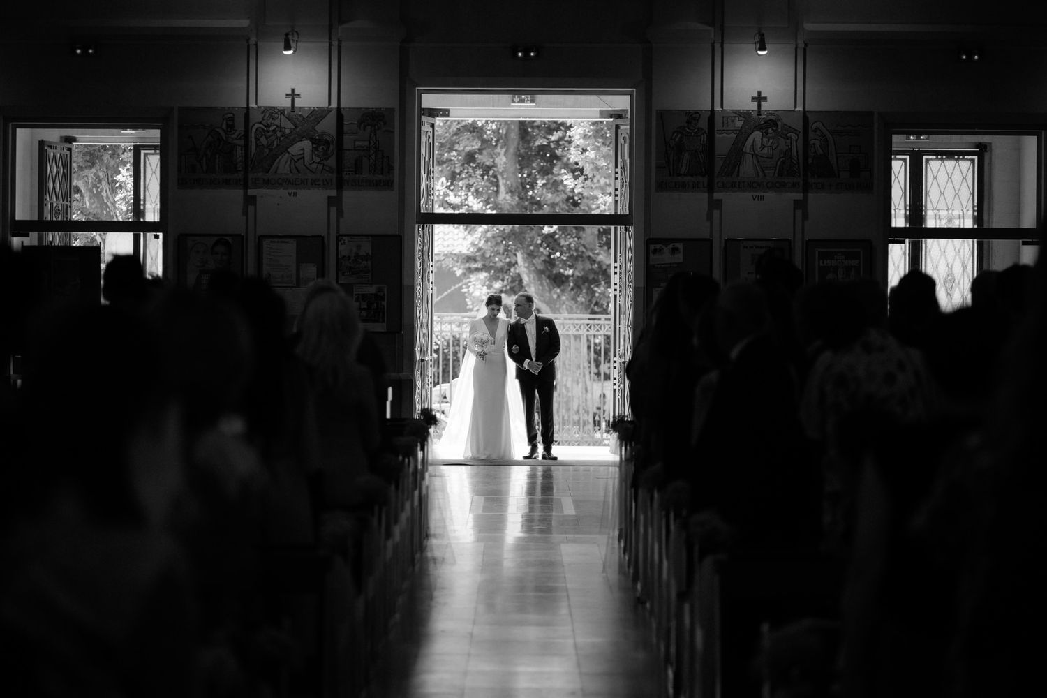 Silhouetted figures in church doorway during wedding ceremony with dramatic backlighting.