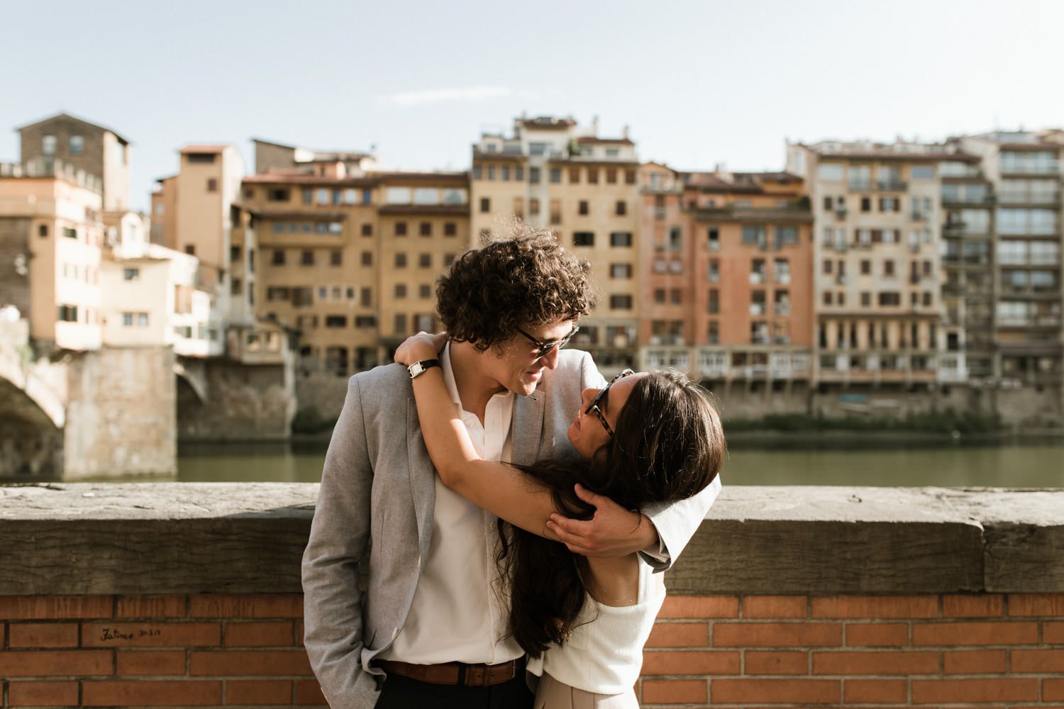 Romantic couple sharing an intimate moment by the Arno River in Florence.