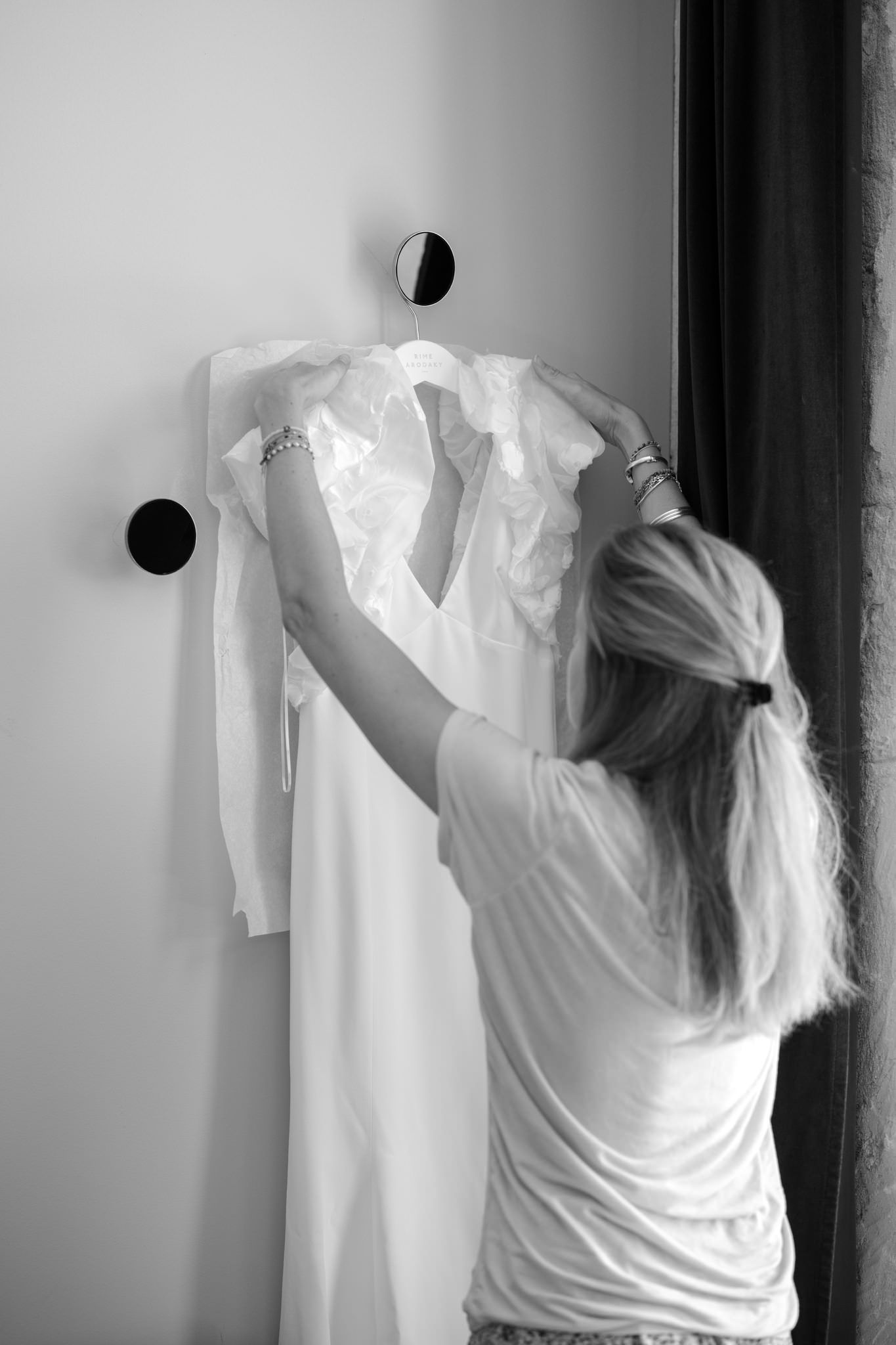 White garments being hung on display against a grey wall.