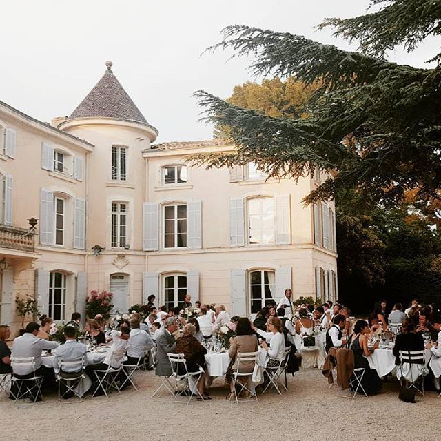 Elegant outdoor wedding reception at a French chateau with guests seated at long tables.