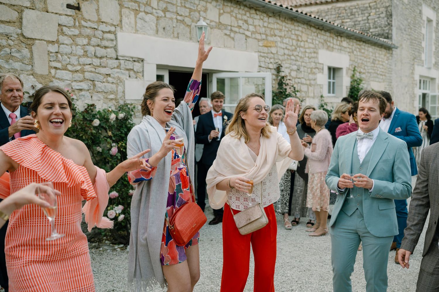 Guests enjoying a lively celebration outside a rustic stone building.