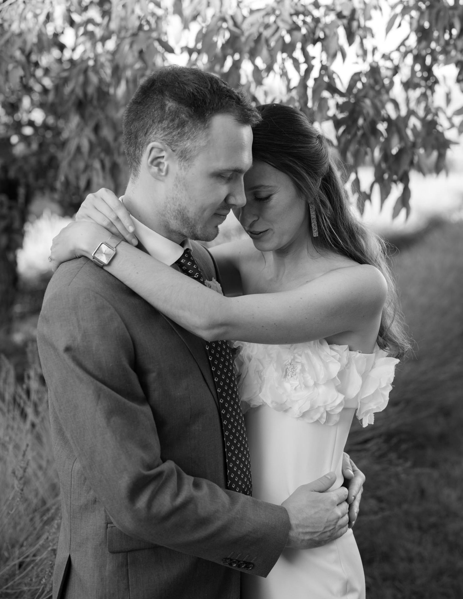 A romantic black and white portrait of newlyweds embracing.