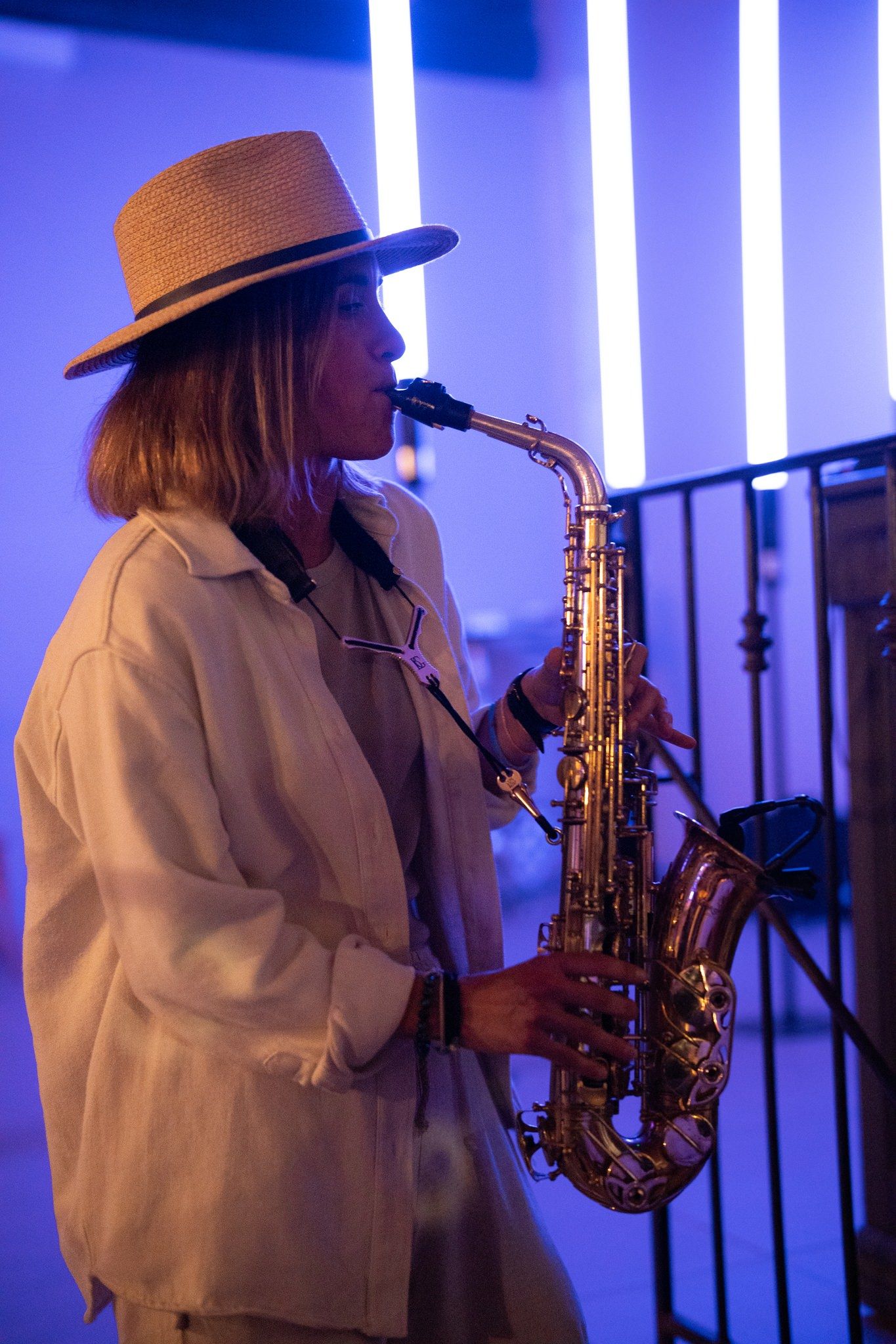 Saxophone performer in white attire illuminated by blue stage lighting.