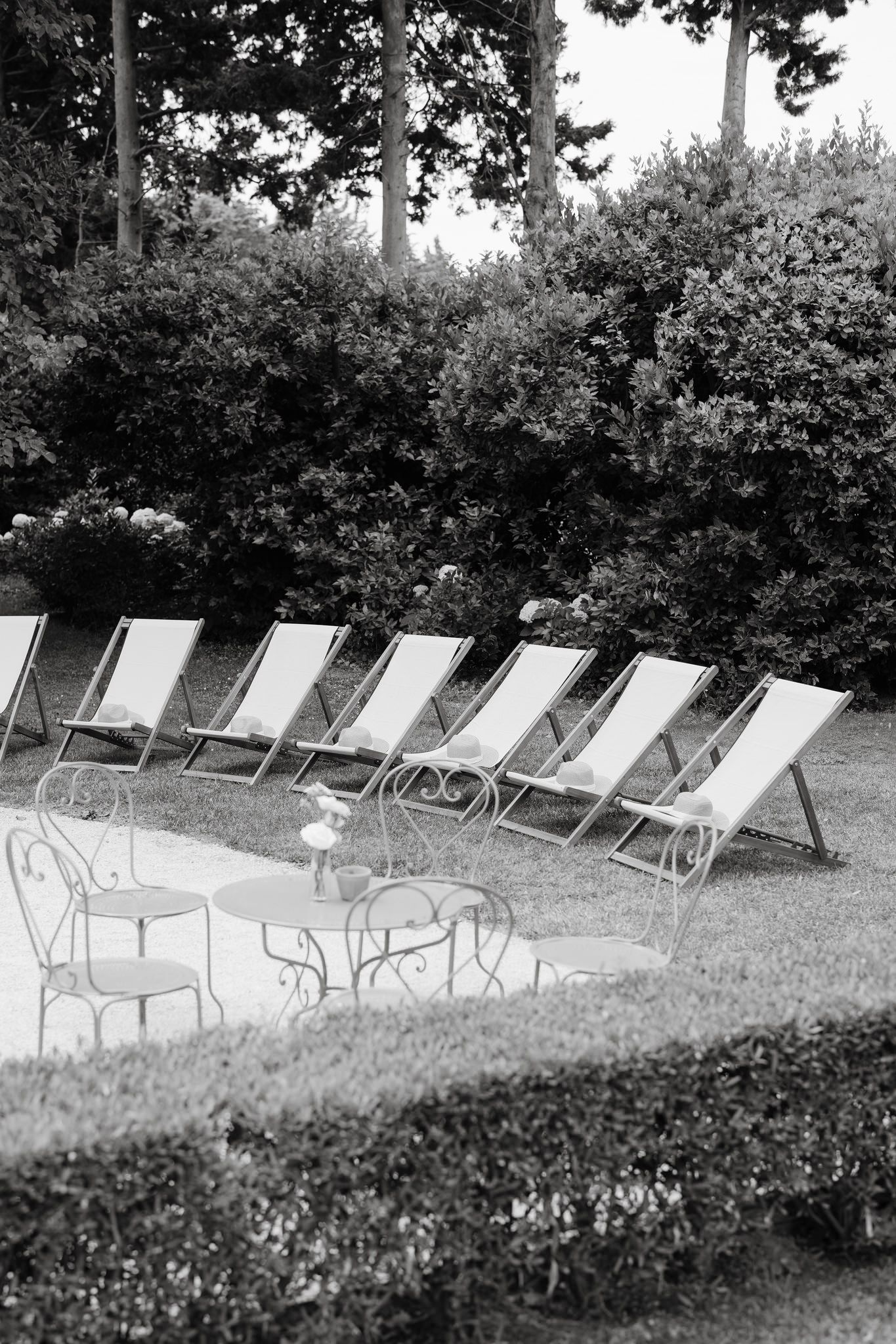 Row of white lounge chairs lined up outdoors in black and white.