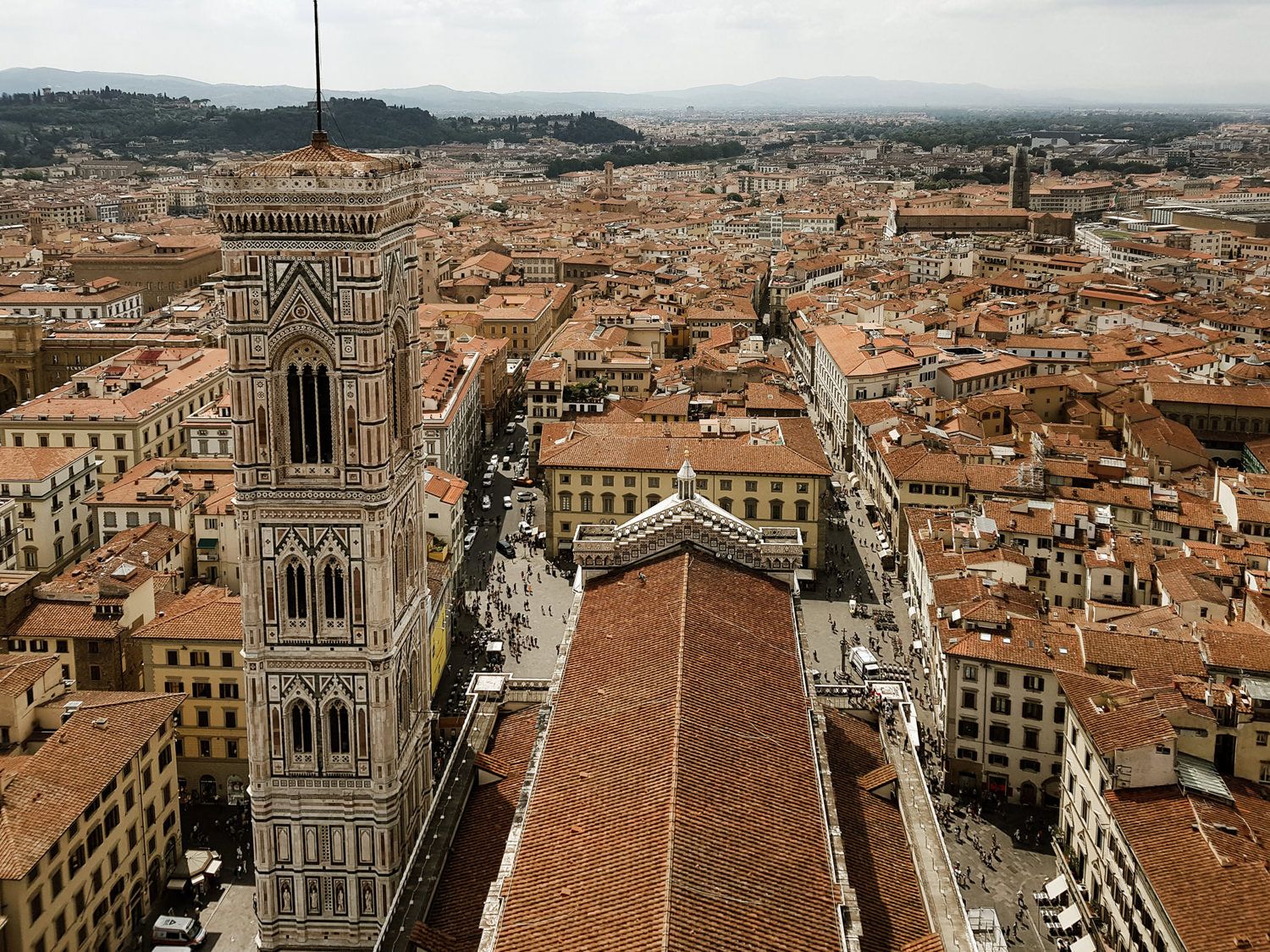 Aerial view of Florence's historic cityscape with Giotto's Bell Tower and terracotta rooftops stretching to the horizon.