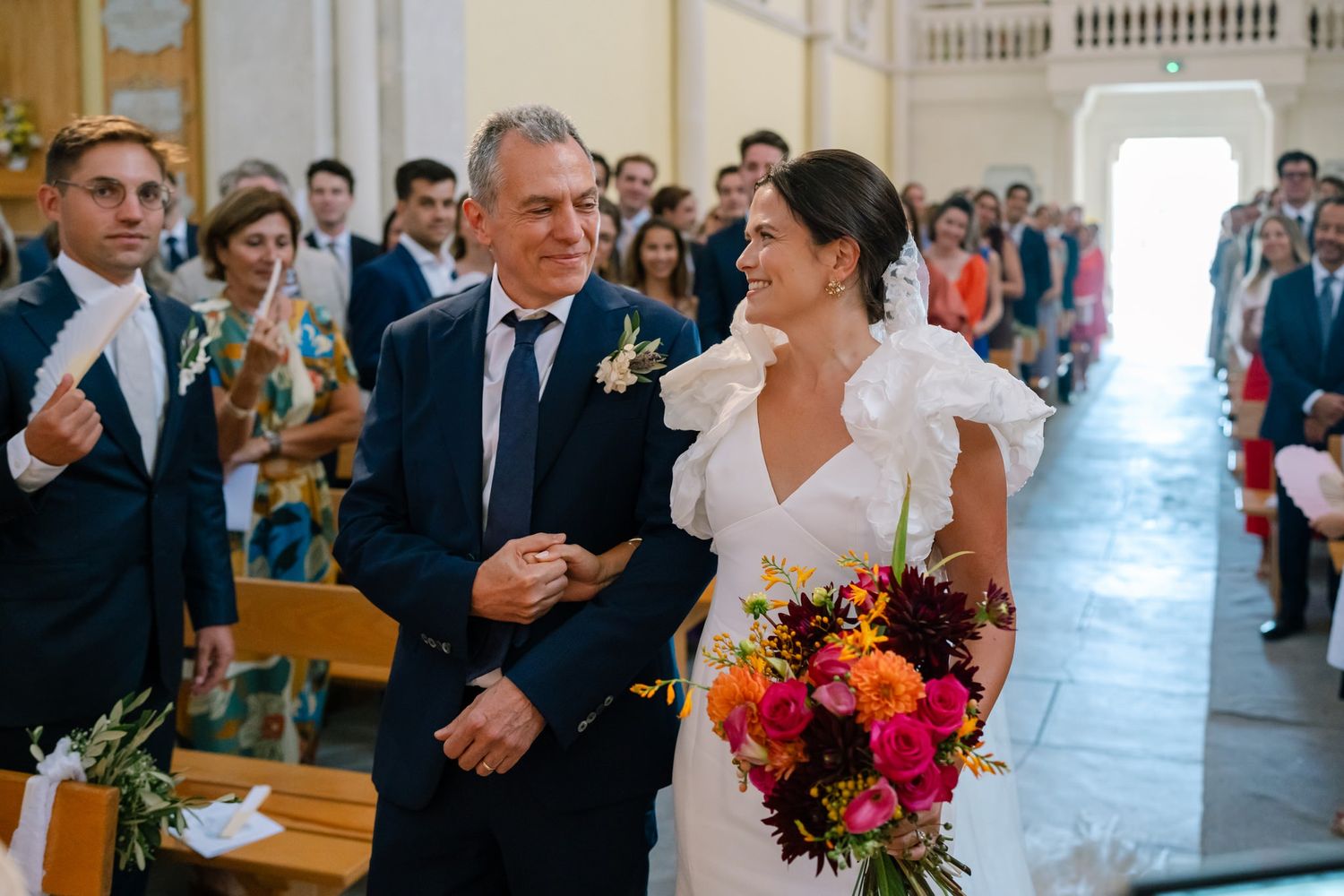A joyful moment during a wedding ceremony with guests looking on from wooden church pews.