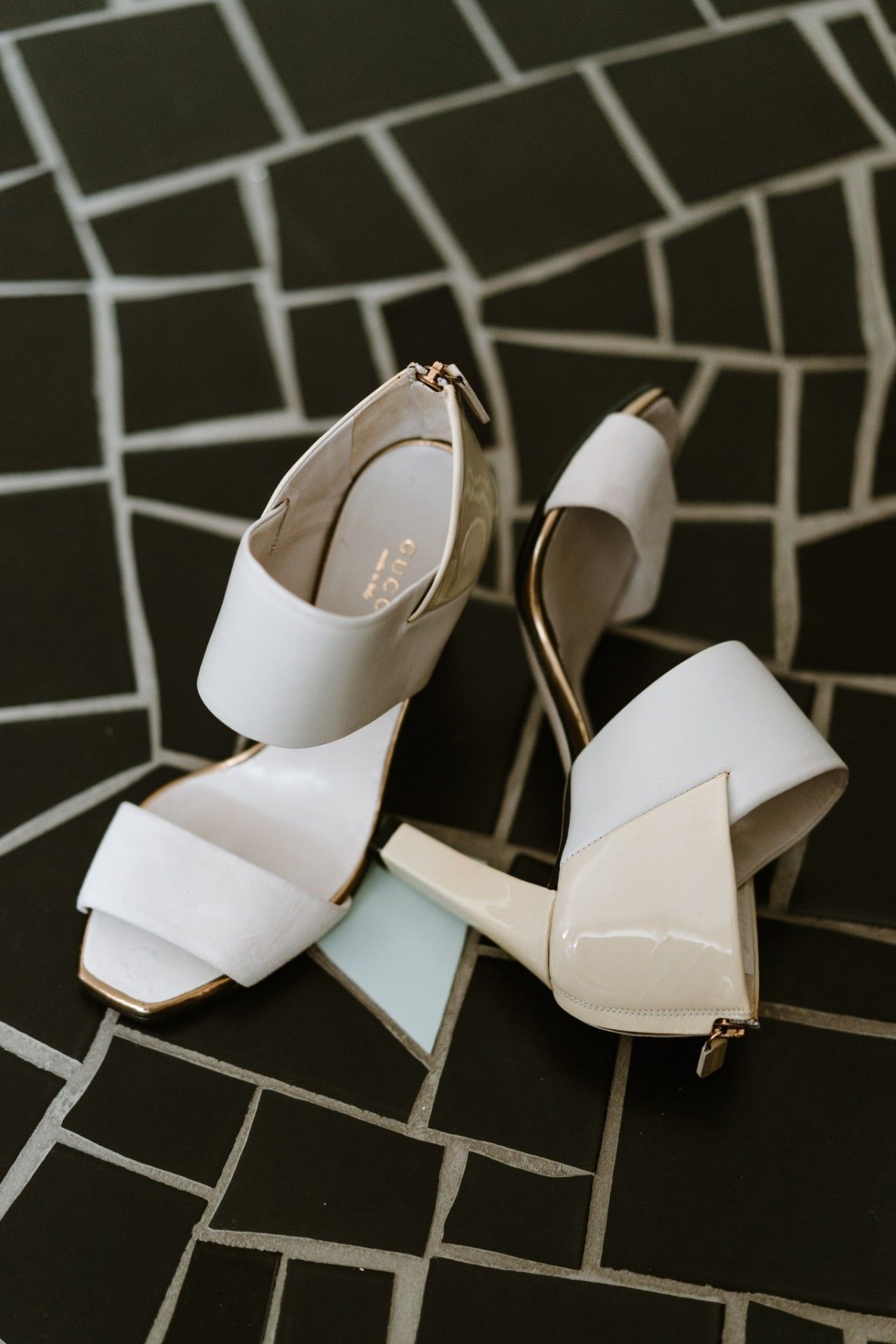 Elegant white bridal heels displayed on a geometric patterned background.