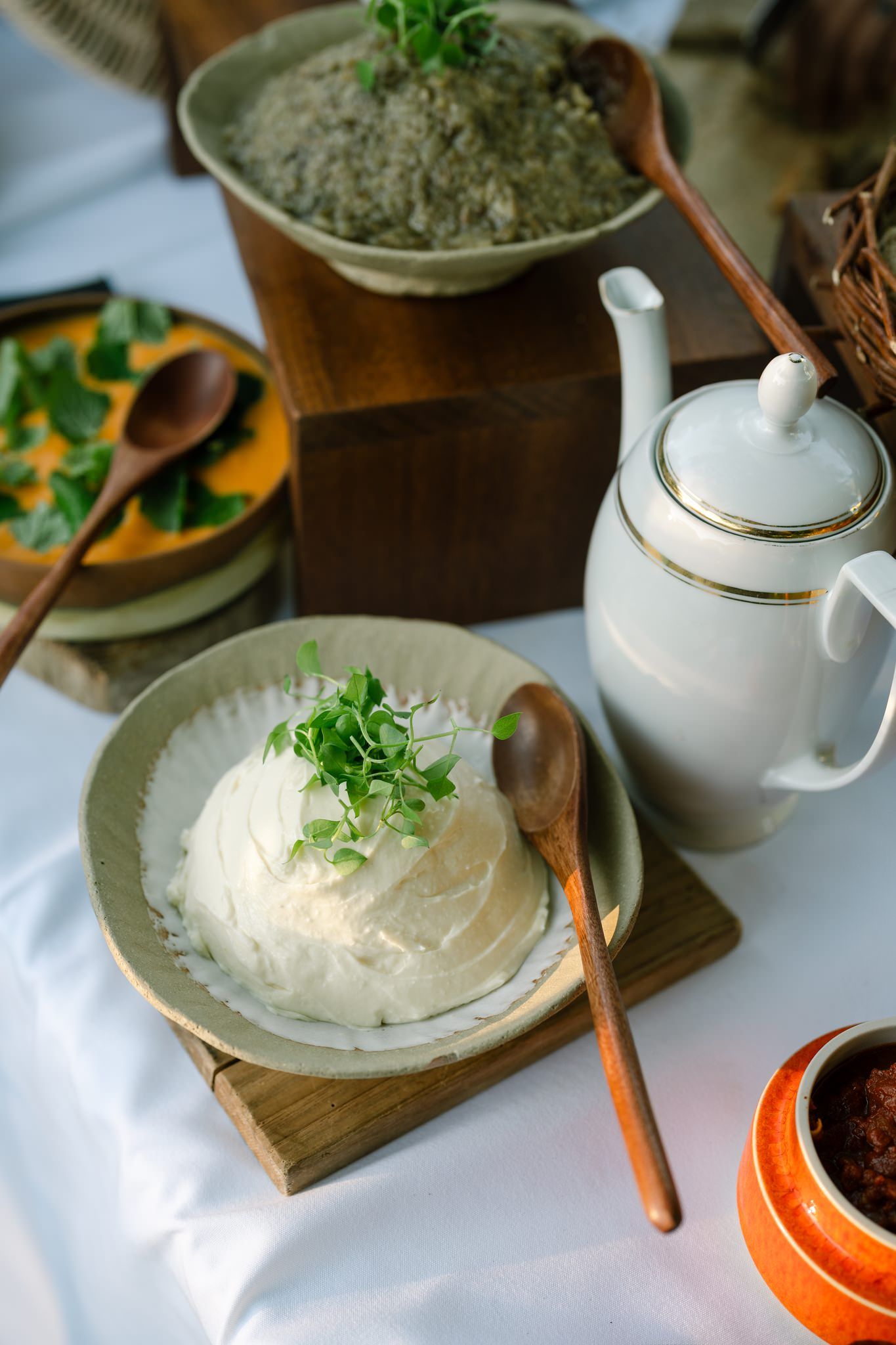 White teapots and cream dishes arranged on rustic wooden surfaces.