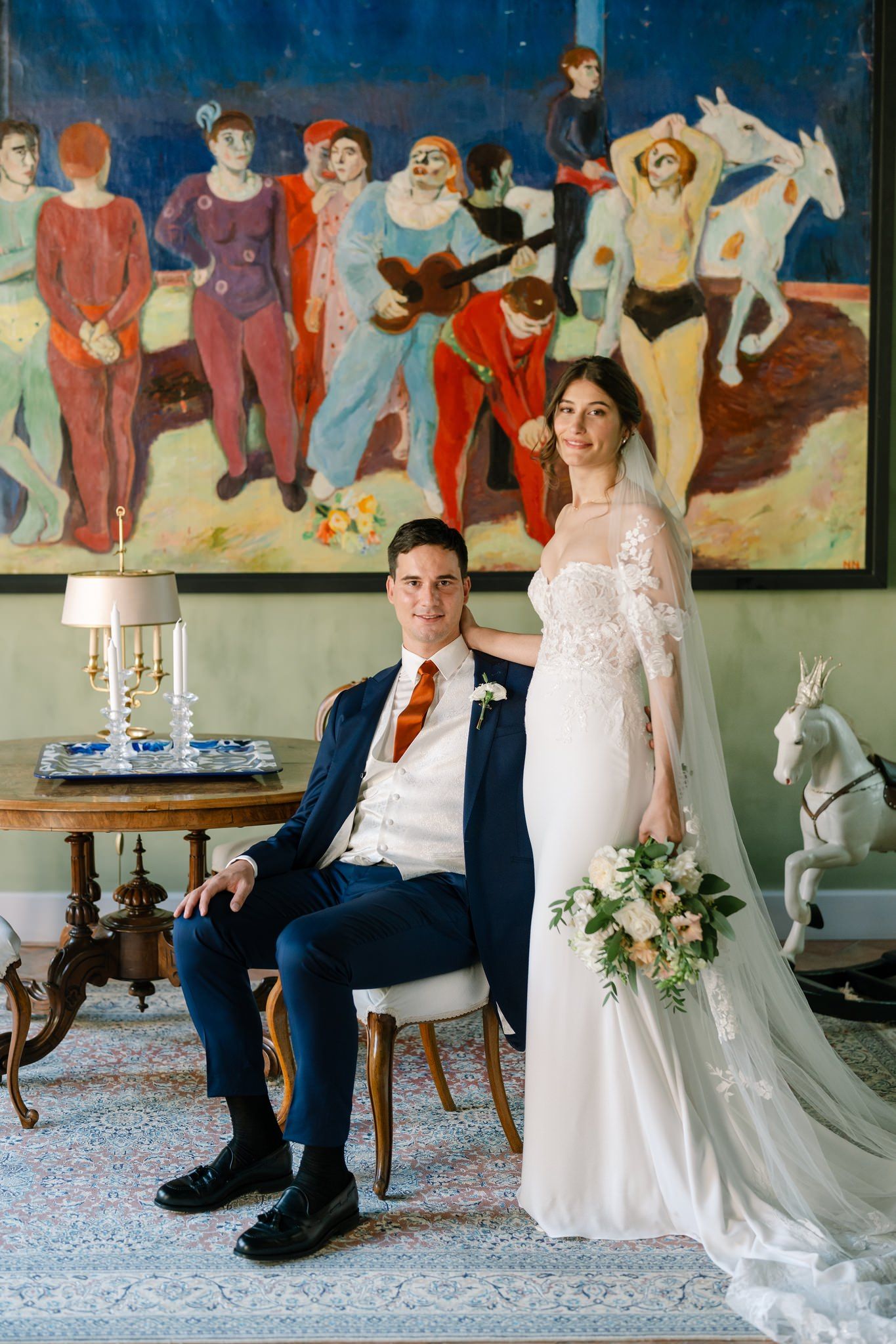 Wedding couple seated in formal room with colorful mural artwork.