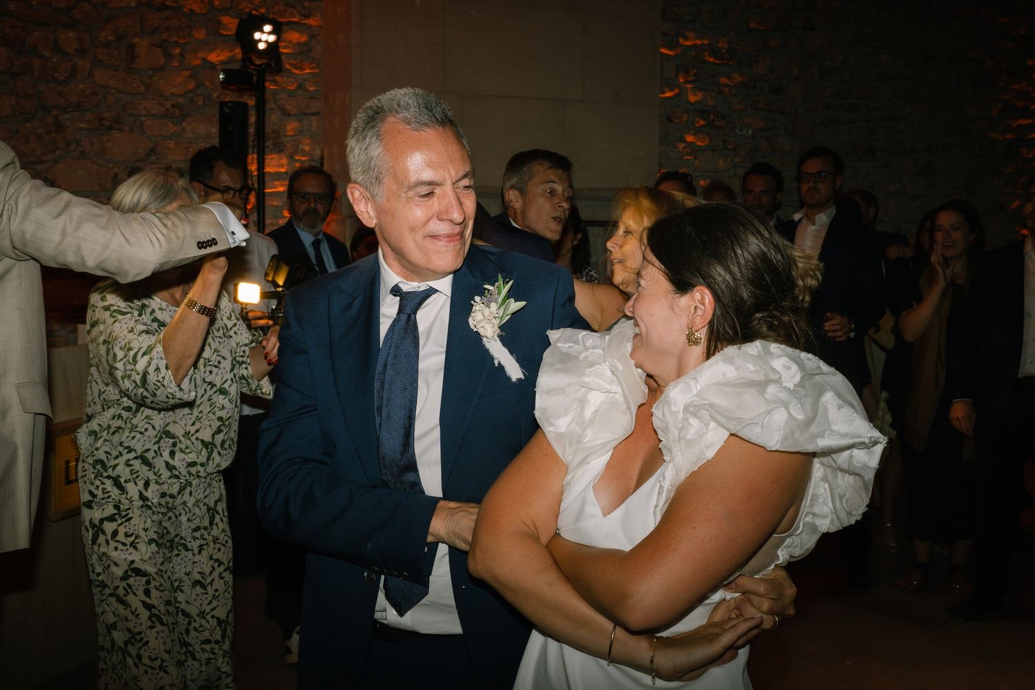 Wedding guests embracing and dancing during an evening celebration.