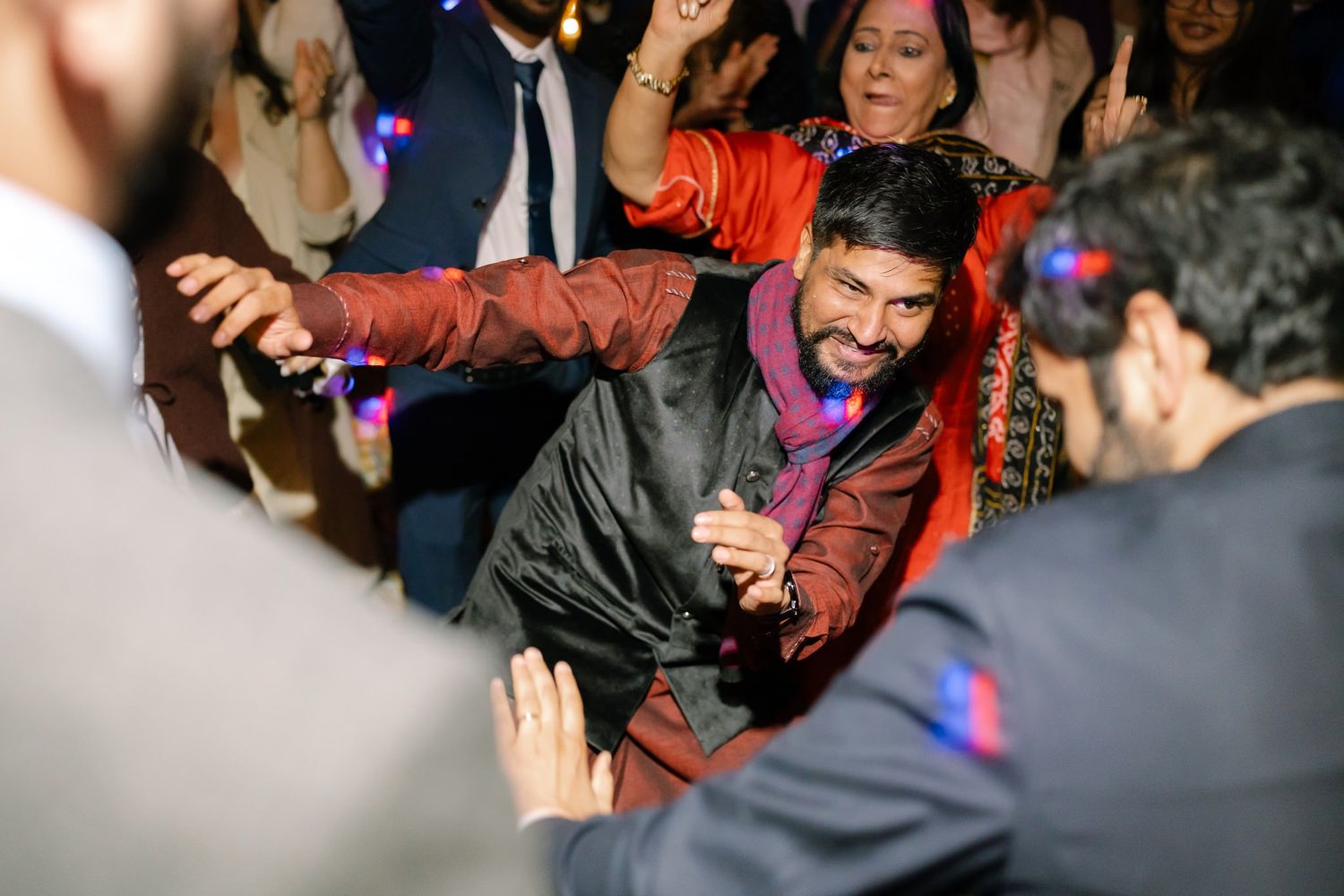 Energetic dancing and celebration on a colorful wedding reception dance floor.