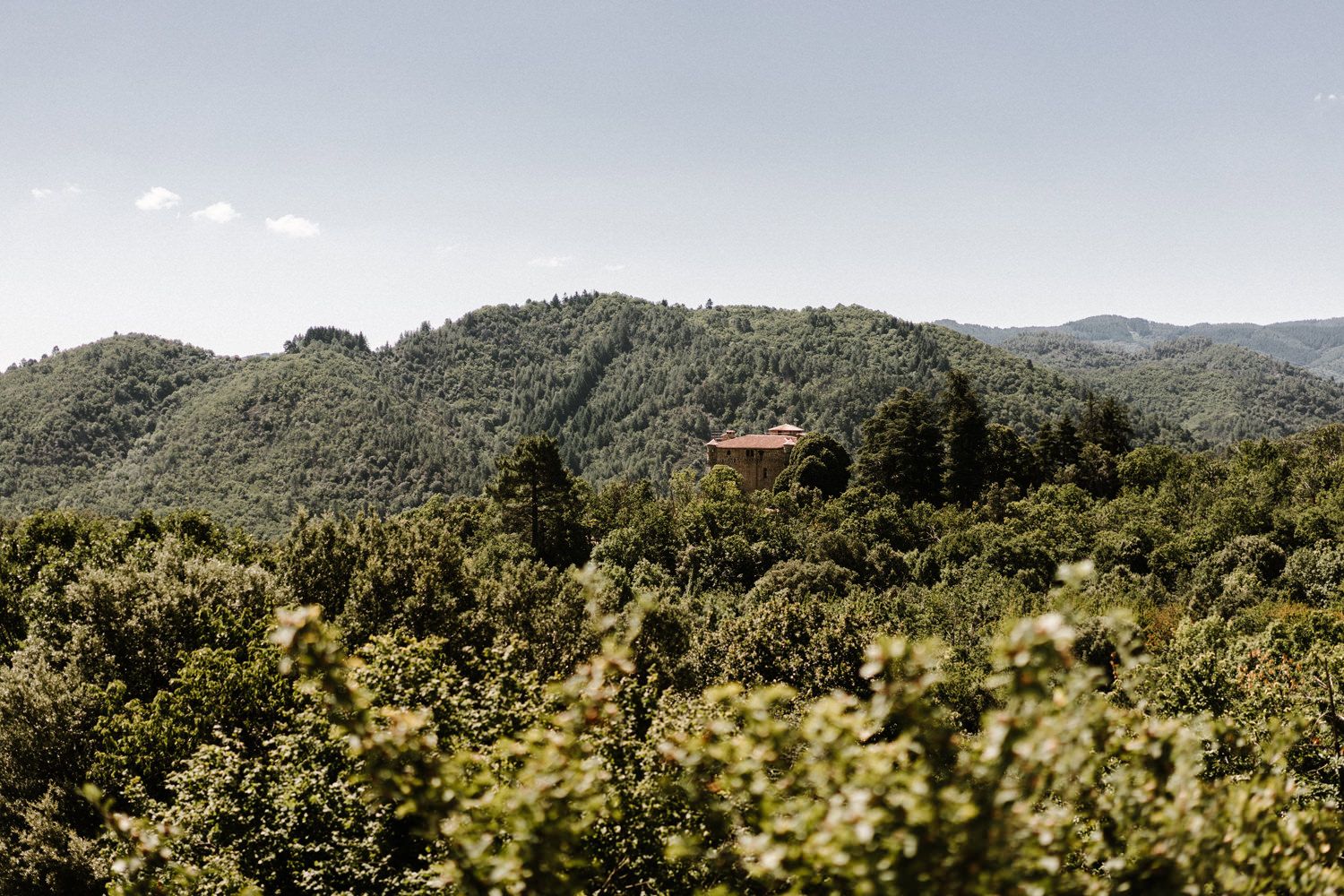 A scenic mountain landscape view with lush green forests and a distant villa.