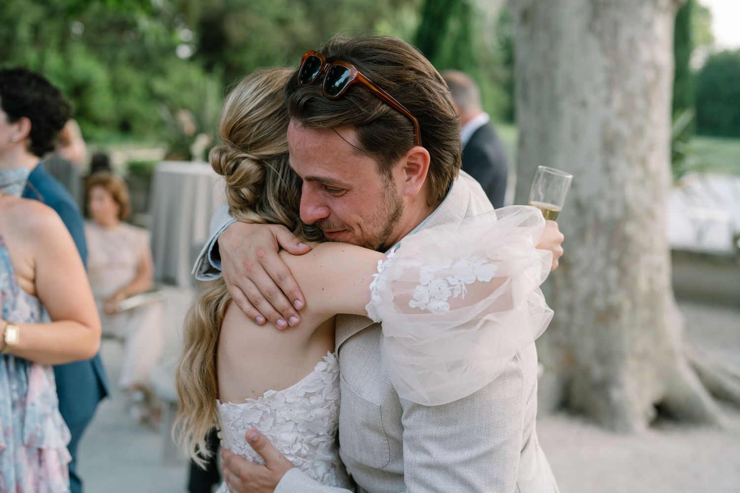 Tender embrace shared between two people at an outdoor wedding celebration.