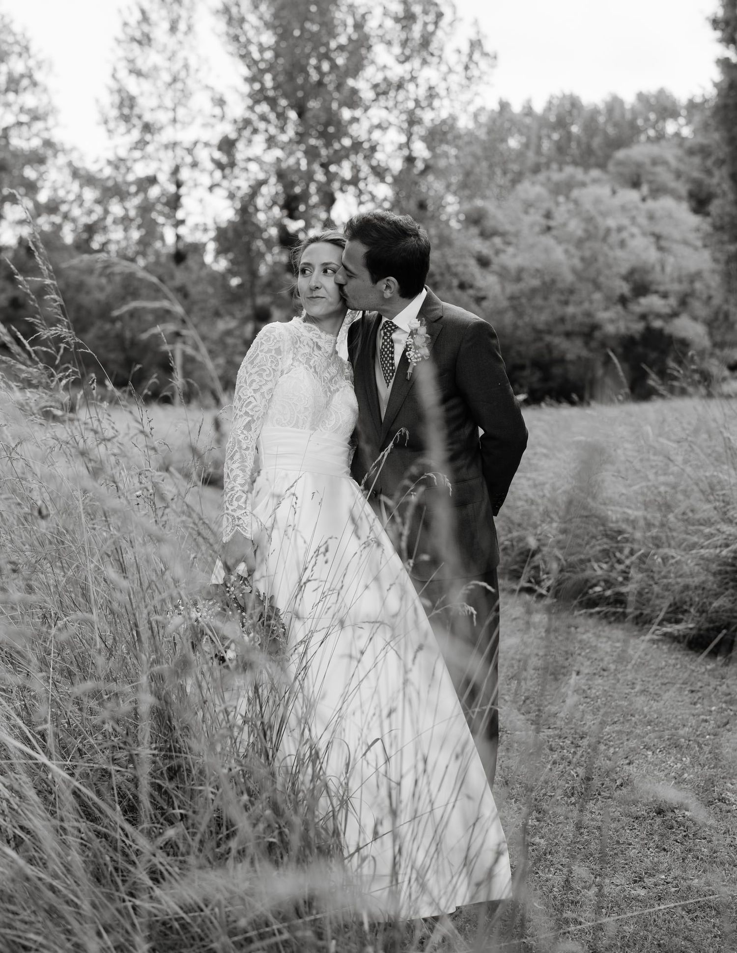 Black and white wedding portraits captured in a rustic field with tall grasses.