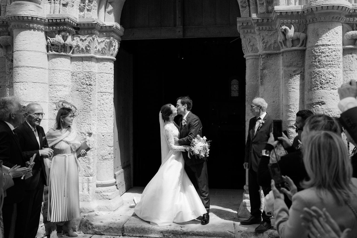 Wedding party and guests celebrating outside historic church architecture.