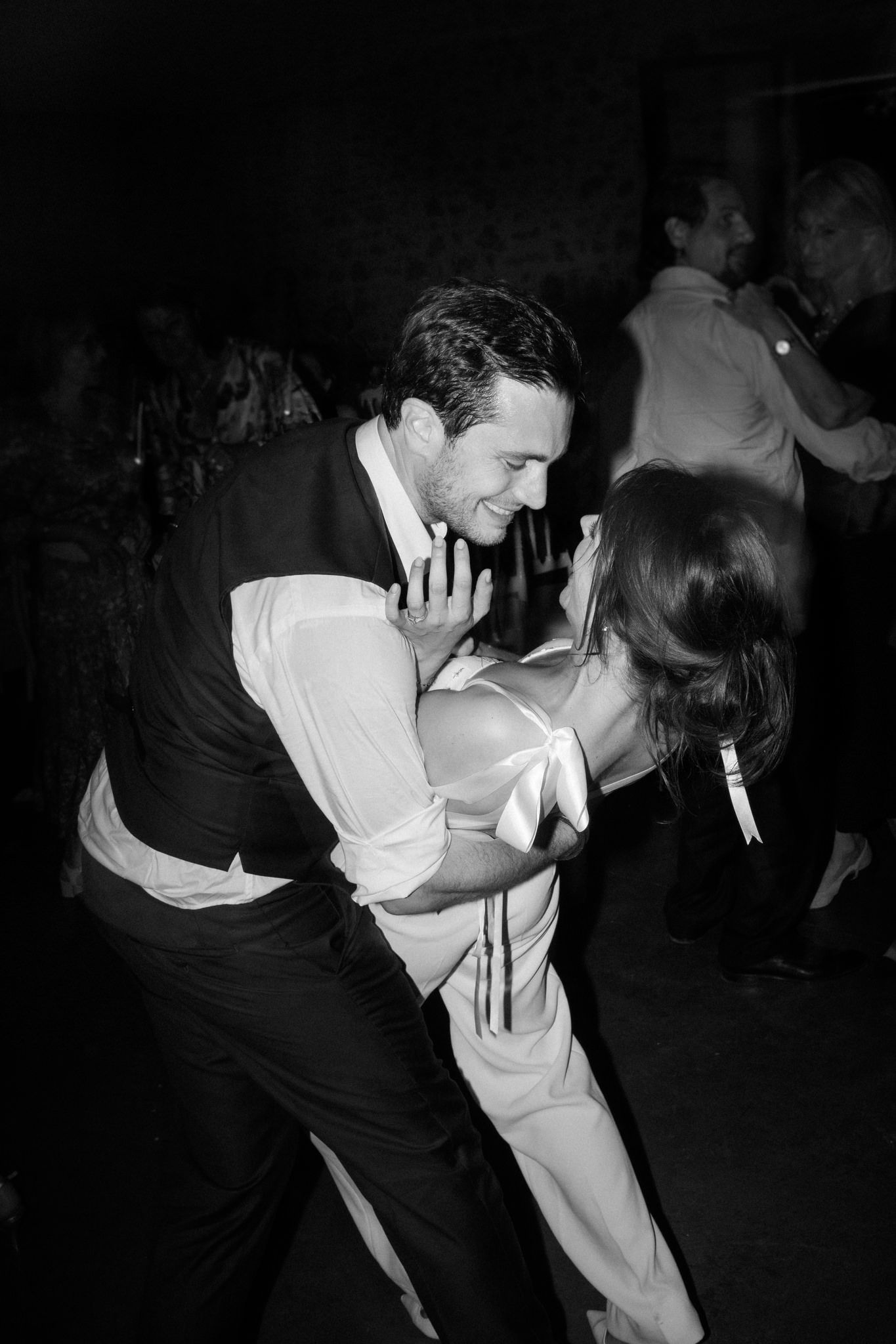 Romantic dance dip sequence captured in black and white at a wedding reception.