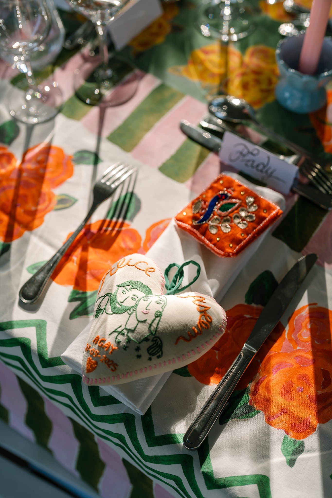 Close-up of table settings with orange floral napkins and green chevron patterns.