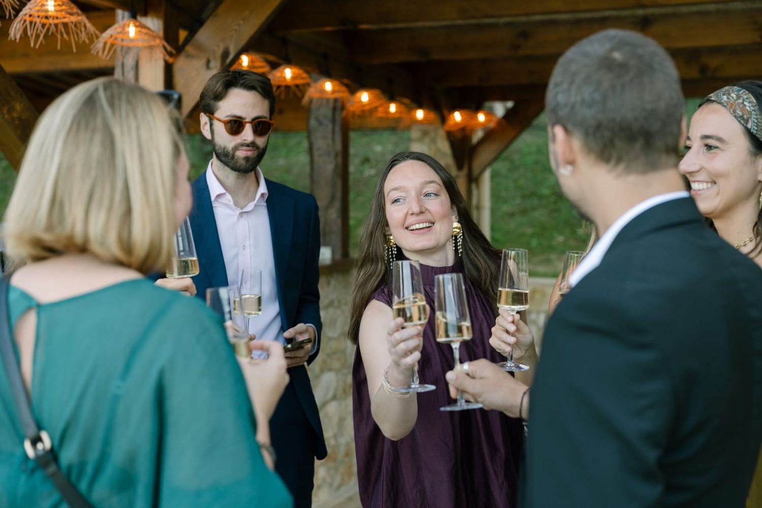 Small group enjoying drinks and conversation at outdoor wedding reception.