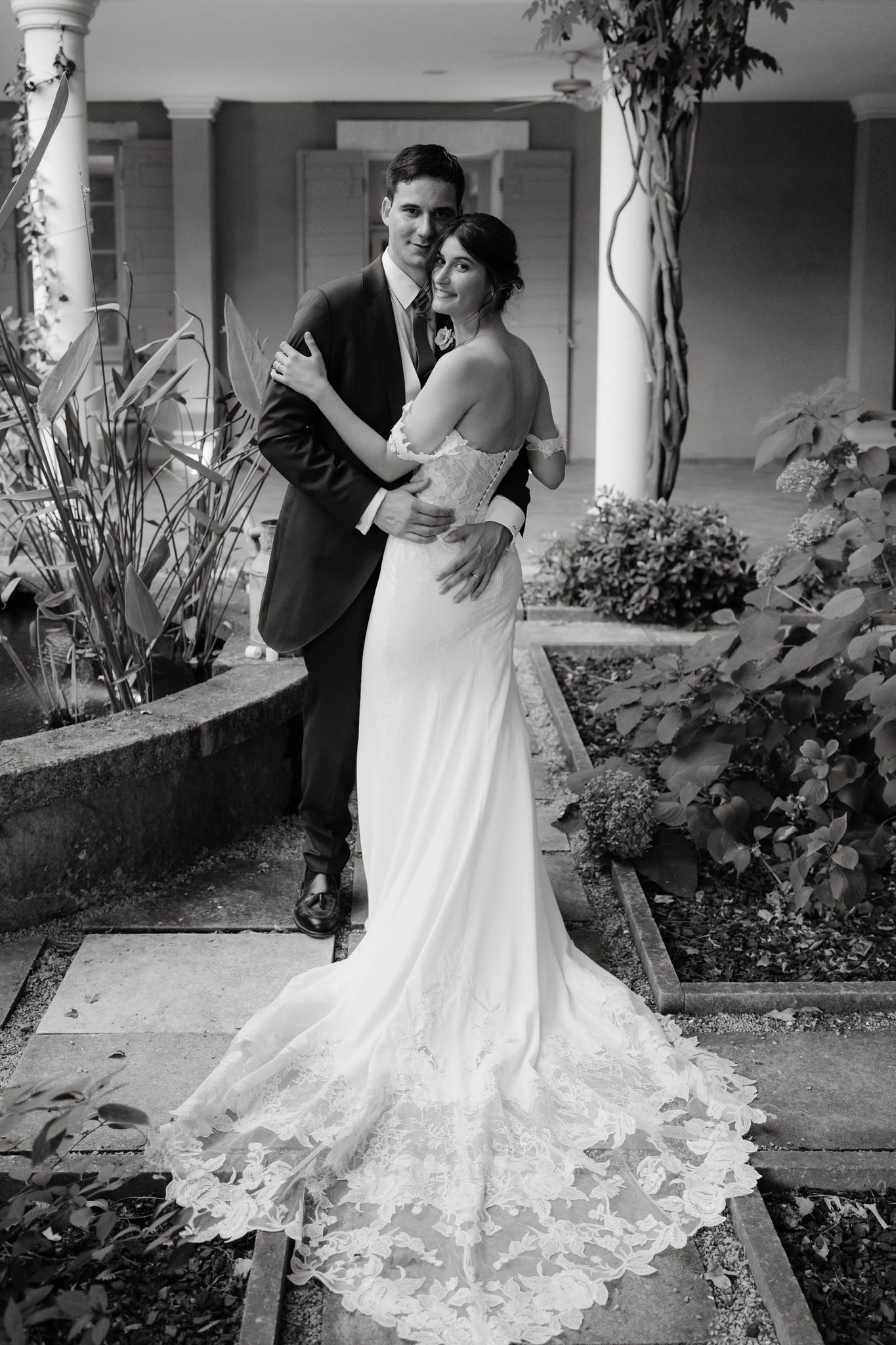 A couple poses together on a garden porch with elegant white columns.