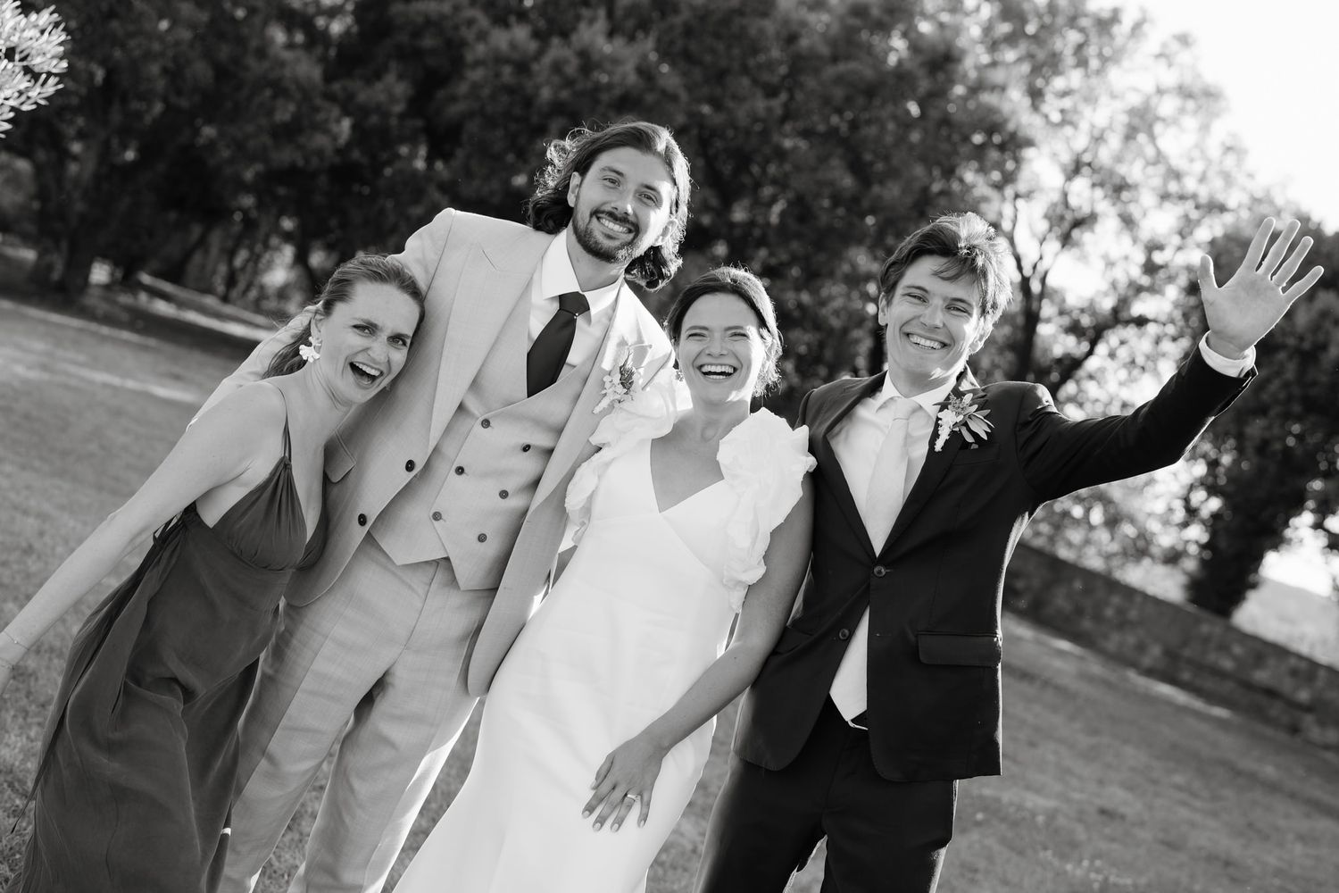 Wedding party poses together outdoors on a sunny afternoon.