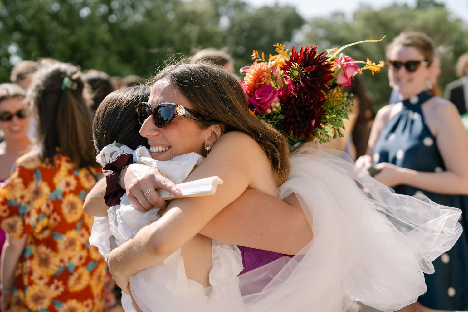 Emotional wedding day hugs shared among guests during outdoor celebration.