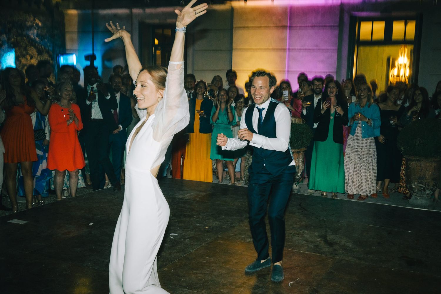 Dancers performing energetic moves on a colorfully lit dance floor.