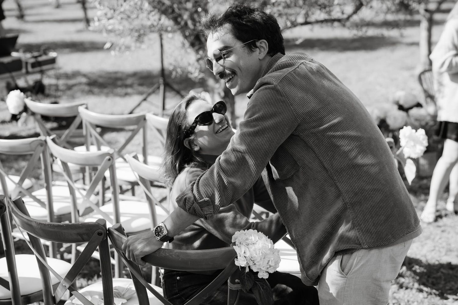 Black and white photograph showing people relaxing on lounge chairs in an outdoor setting.