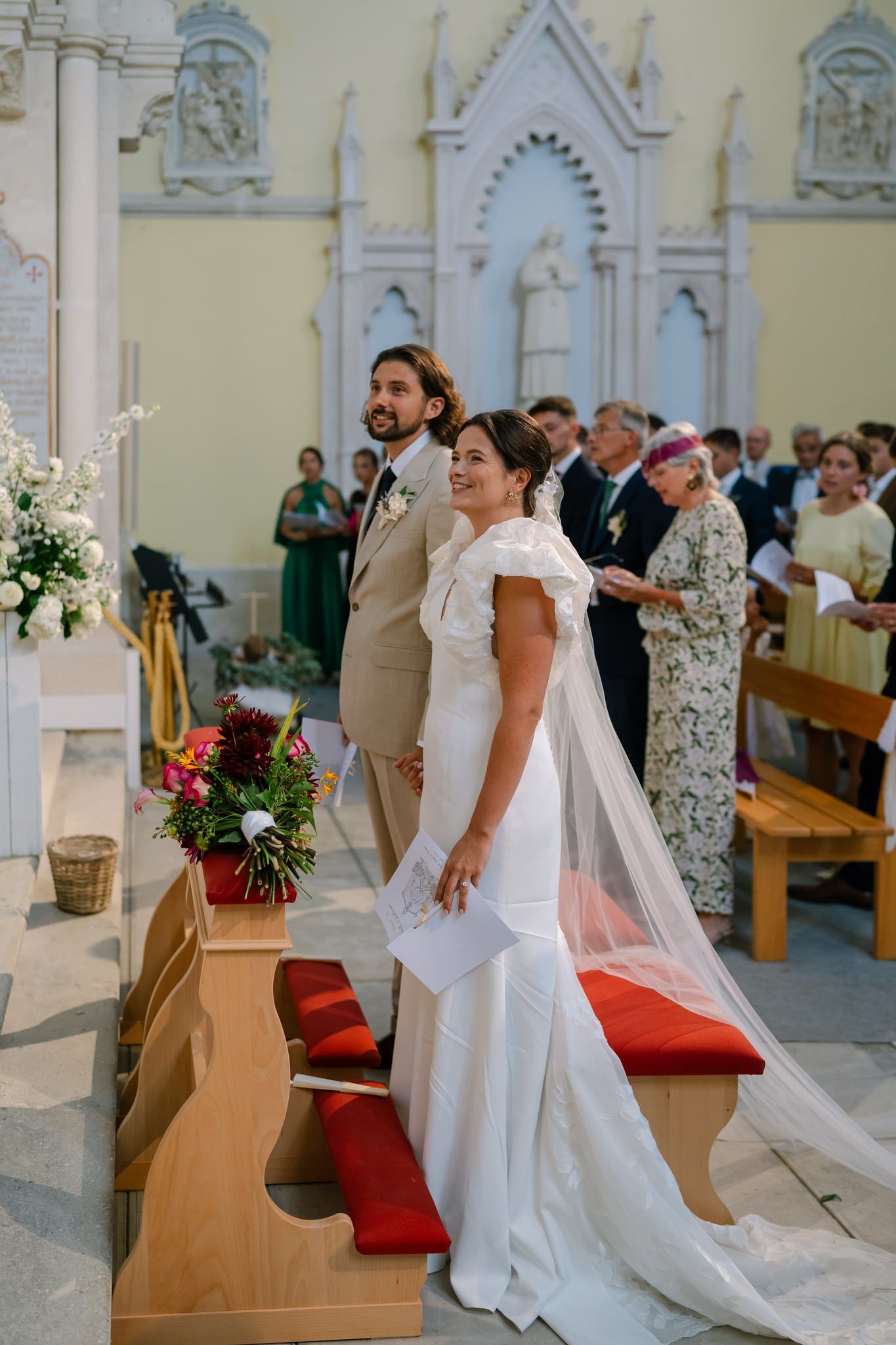 A couple stands at the altar of an ornate church during their wedding ceremony.