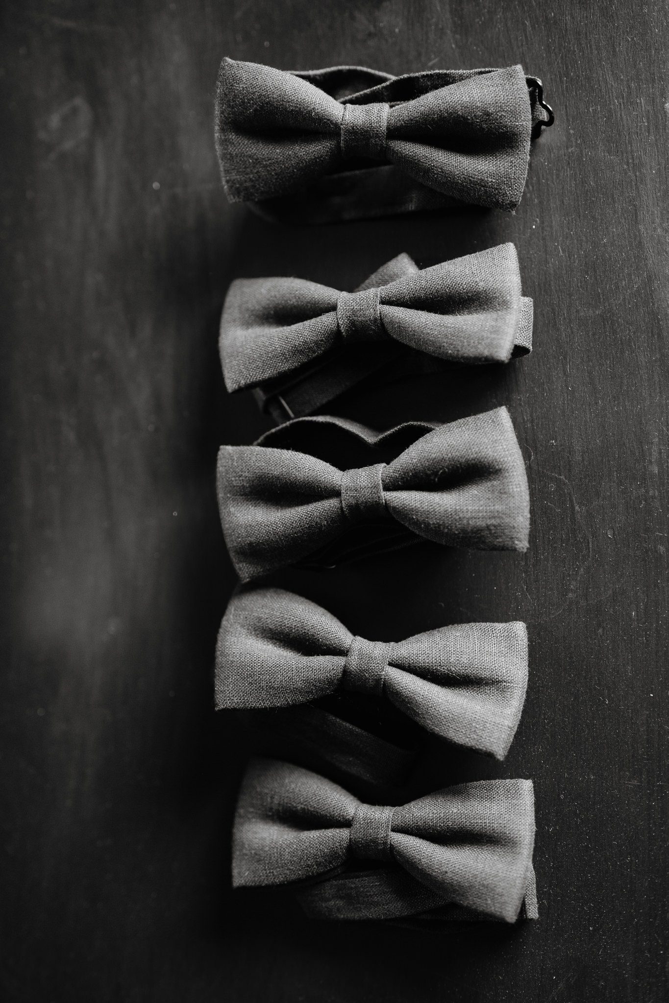 Row of gray bow ties arranged in a line against dark background.