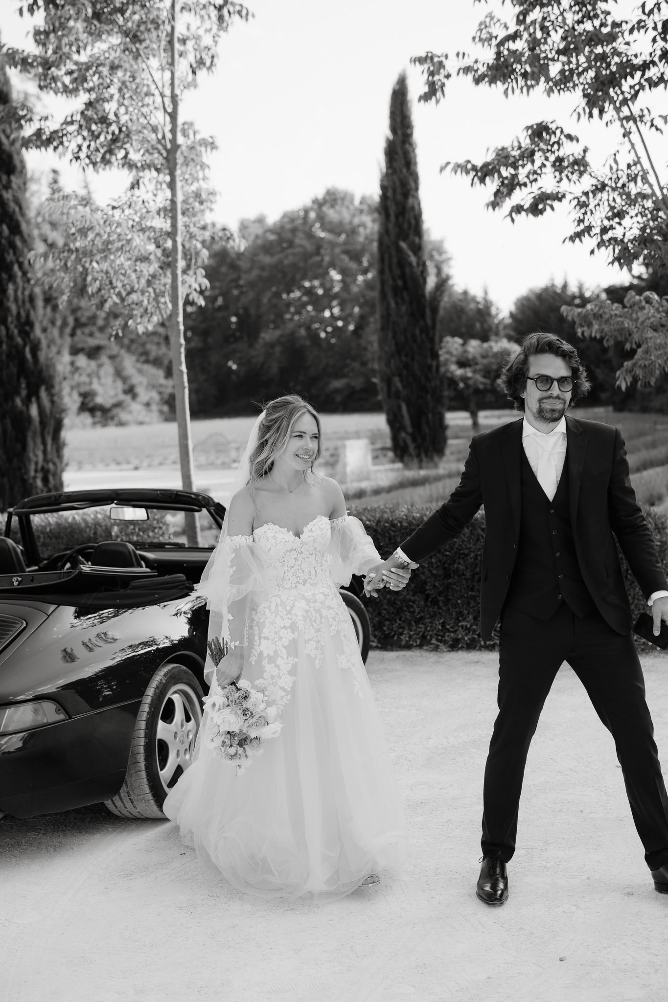 Black and white wedding photos capture playful moments between newlyweds in an outdoor setting.