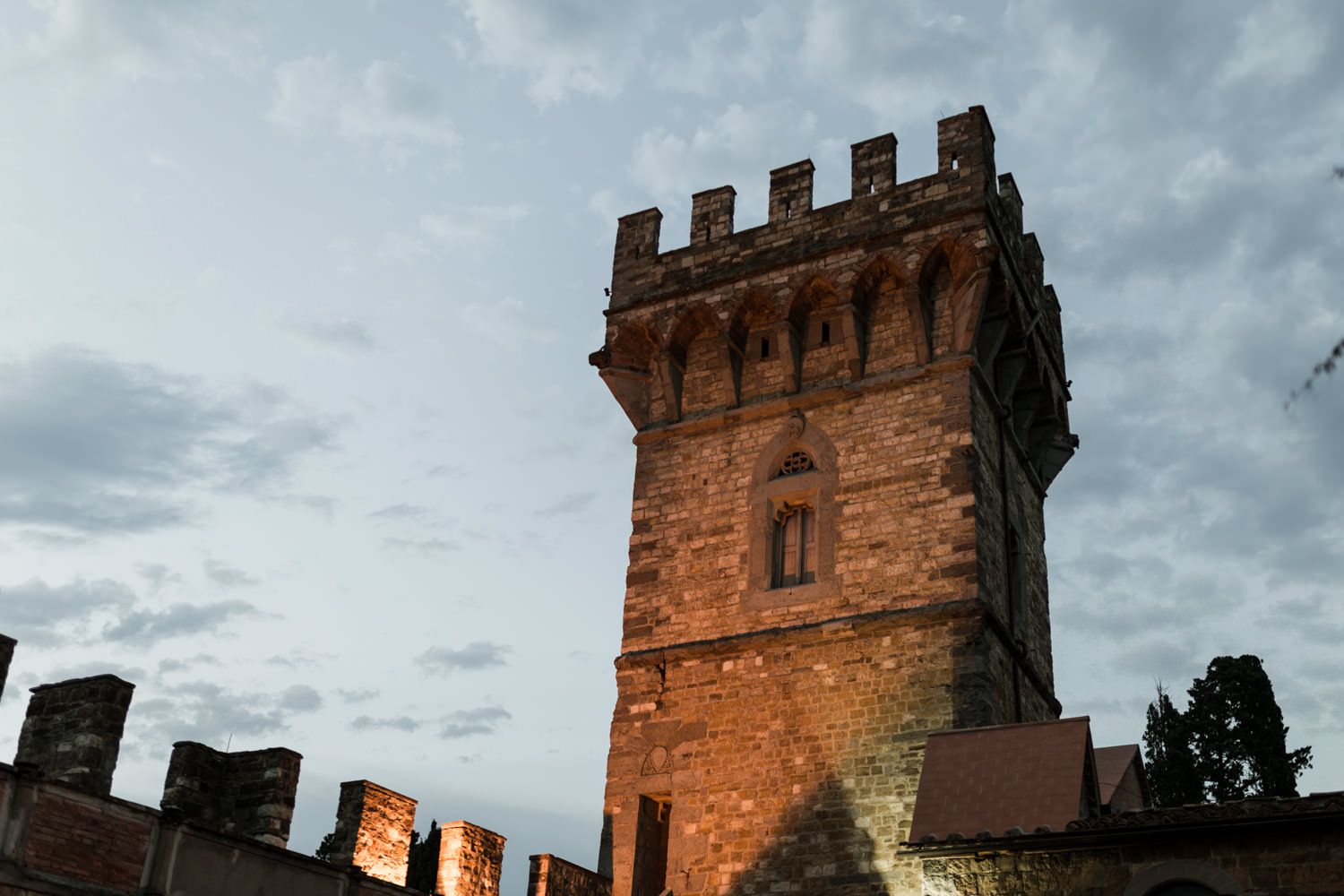 Ancient stone castle tower with crenellated top against moody evening sky.