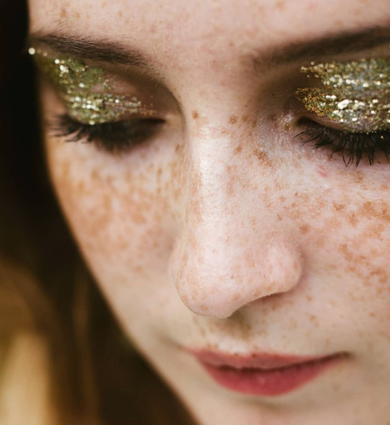 Close-up detail of freckles and natural makeup on skin.