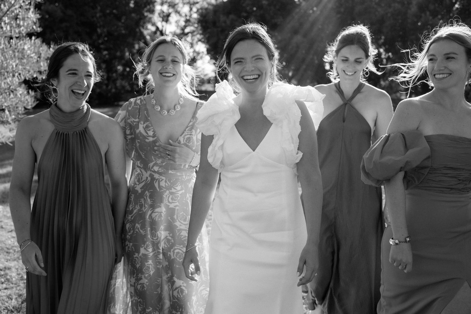 Wedding party members laughing together in a candid black and white photo.