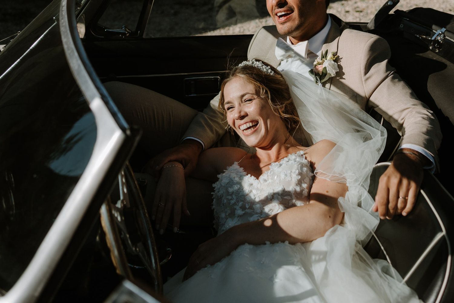 A joyful moment captured inside a vintage convertible car on a sunny day.