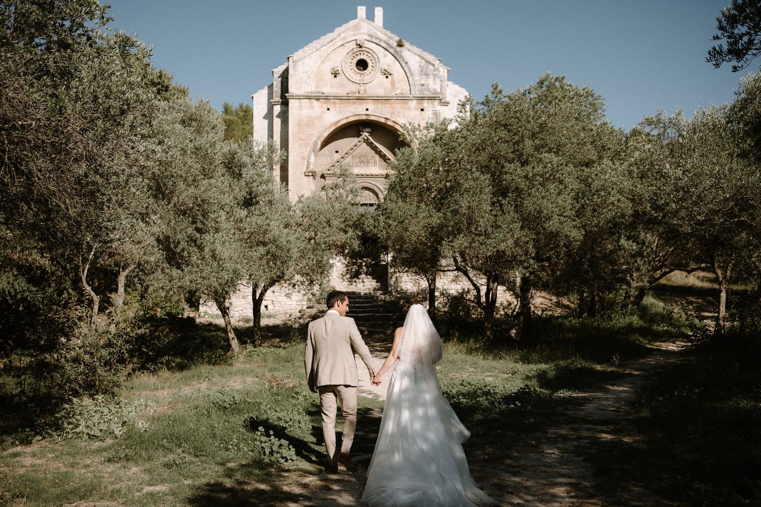 Stone church and olive trees create a romantic wedding venue backdrop.